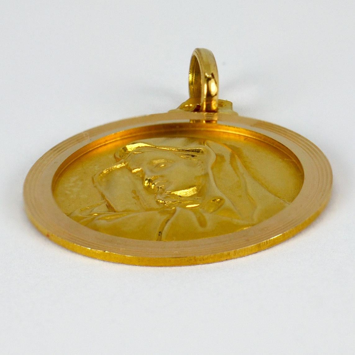 An 18 karat (18K) yellow gold pendant designed as a round medal depicting the Virgin Mary. Stamped with the eagle’s head for French manufacture and 18 karat gold, with unknown maker’s mark.

Dimensions: 2.6 x 2.2 x 0.13 cm (not including jump