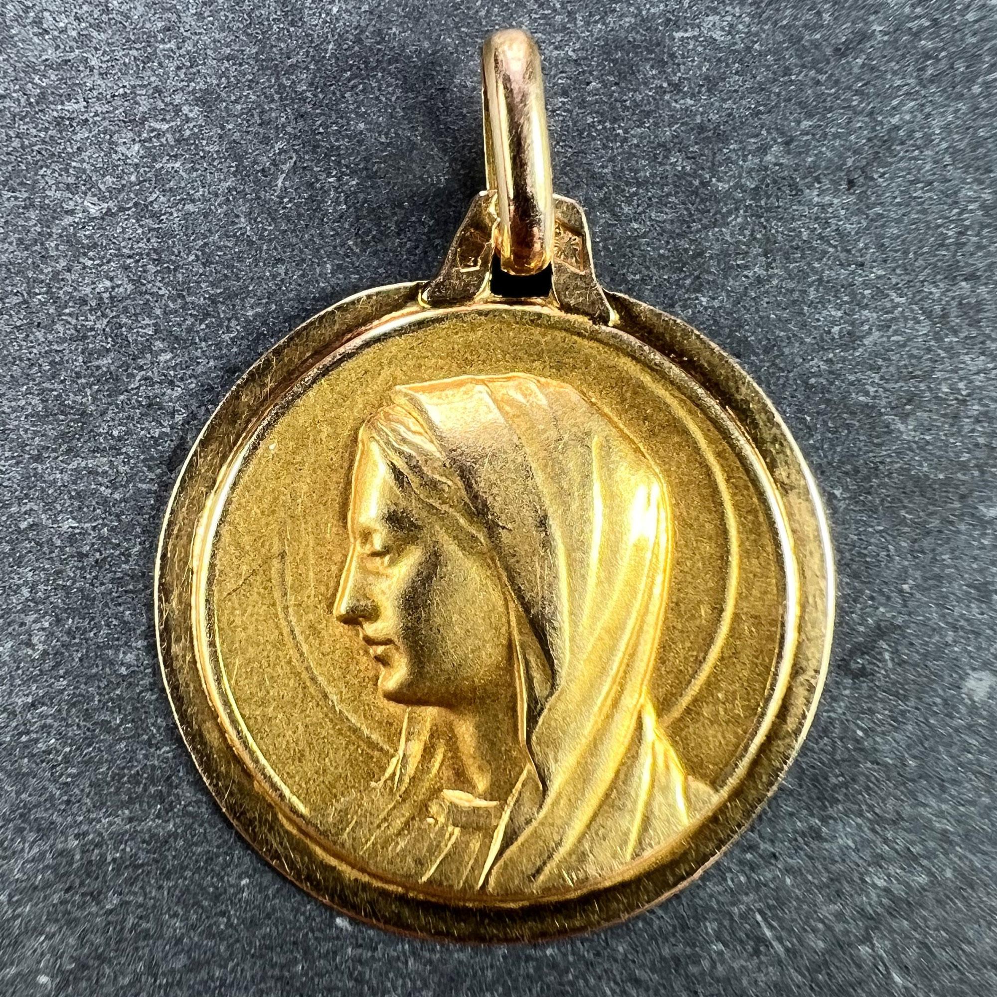 An 18 karat (18K) yellow gold pendant designed as a round medal depicting the Virgin Mary with a halo. Stamped with French marks for 18 karat gold with an unknown maker's mark.

Dimensions: 2.1 x 1.8 x 0.13 cm (not including jump ring)
Weight: 1.41