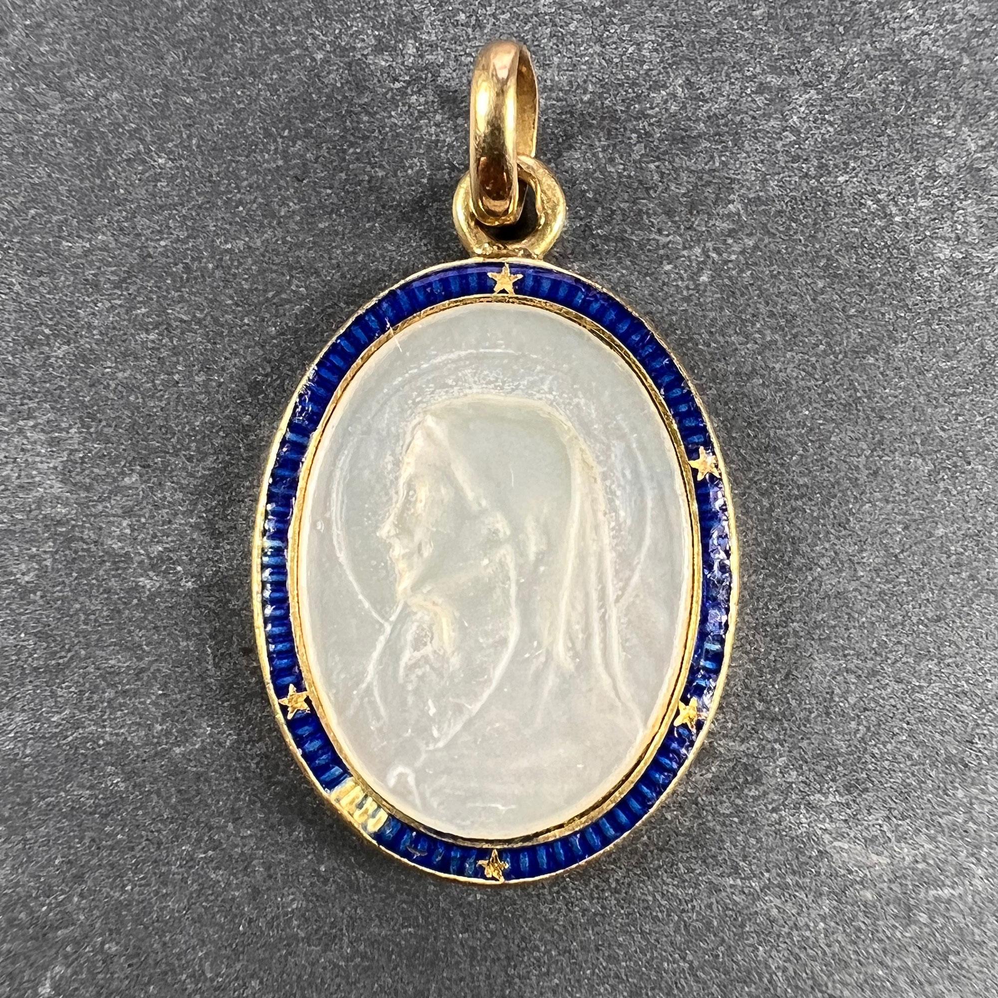 A French 18 karat (18K) yellow gold charm pendant  designed as a mother of pearl medal depicting the Virgin Mary surrounded by a blue enamel border with gold stars. Small chips to the enamel and one star lost. Stamped with the eagle mark for 18
