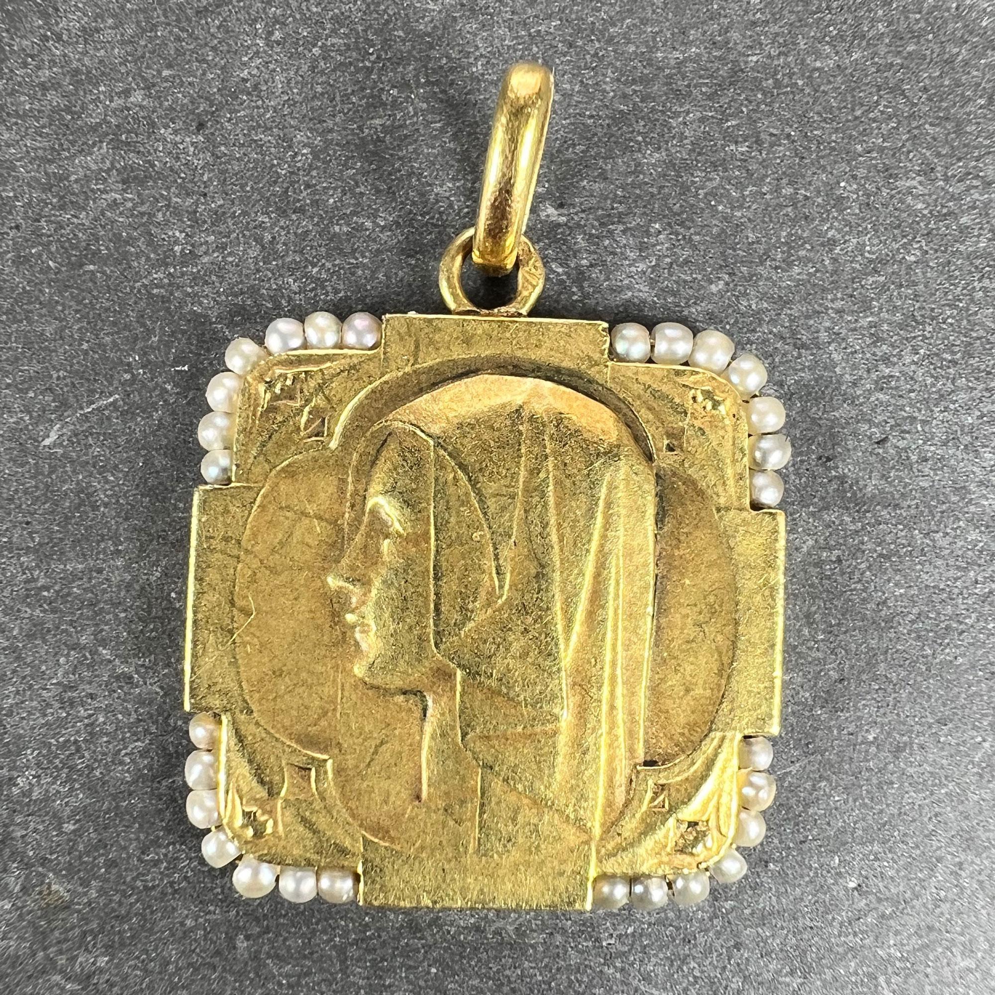 A French 18 karat (18K) yellow gold charm pendant designed as a medal depicting the Virgin Mary surrounded at the corners by a seed pearl border with 28 natural seed pearls. Stamped with the eagle mark for 18 karat gold and French manufacture with
