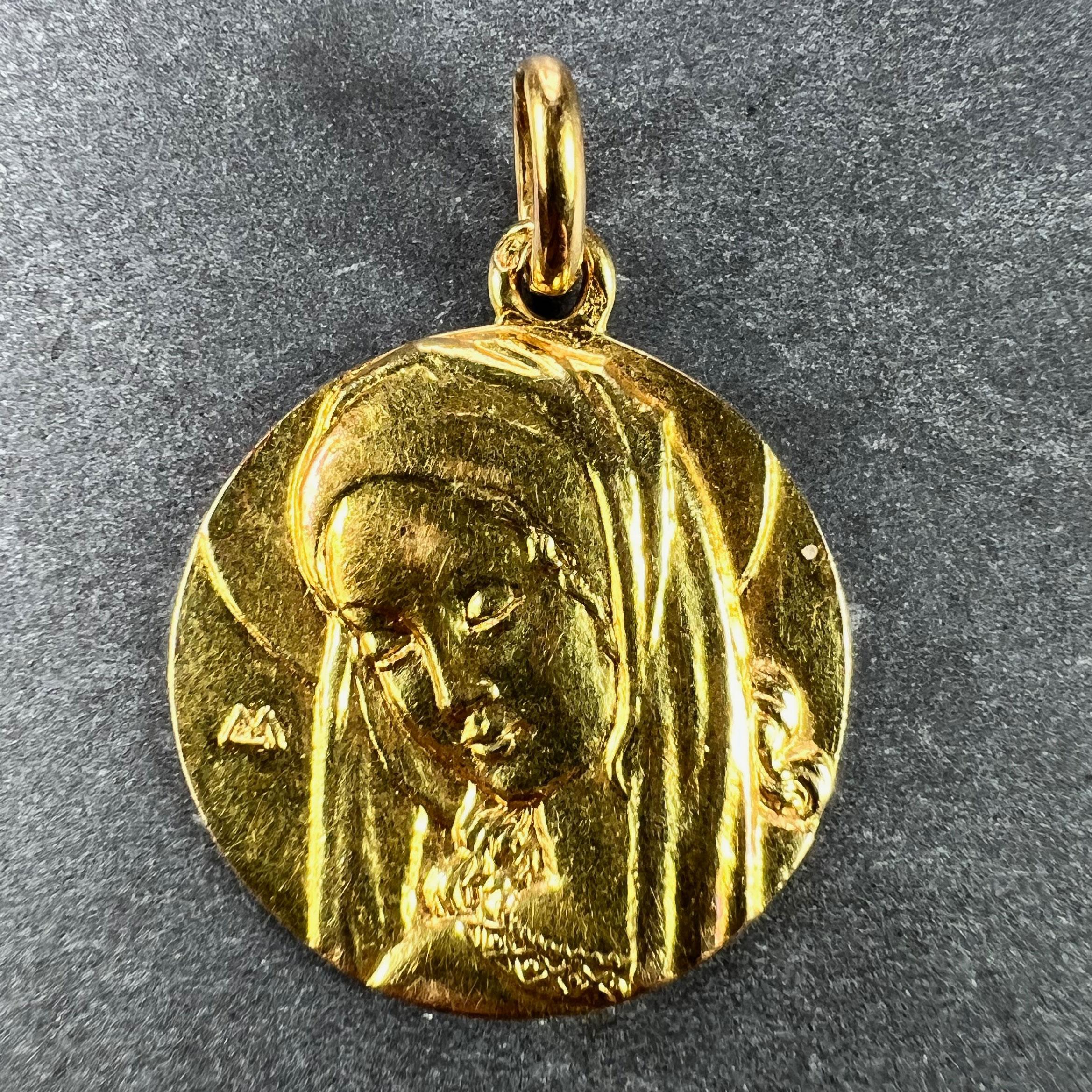 A French 18 karat (18K) yellow gold charm pendant designed as a medal depicting the Virgin Mary. Stamped with the eagle's head mark for 18 karat gold and French manufacture and an unknown maker's mark.

Dimensions: 2.1 x 1.8 x 0.15 cm (not including