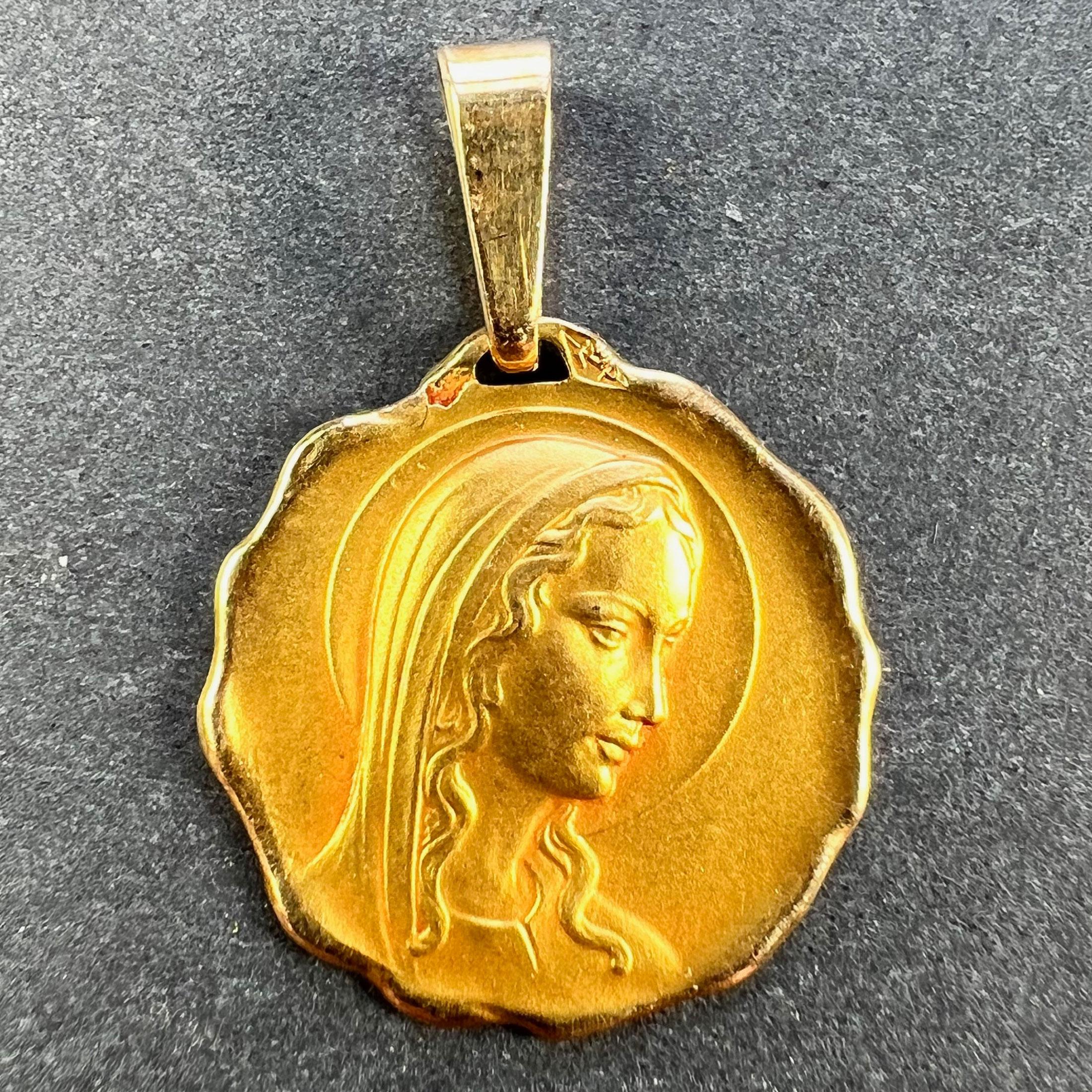 Colgante francés de oro amarillo de 18 quilates (18K) diseñado como una medalla redonda que representa a la Virgen María dentro de un halo y un marco ondulado. Con sello de cabeza de águila de fabricación francesa y oro de 18 quilates, con marca de