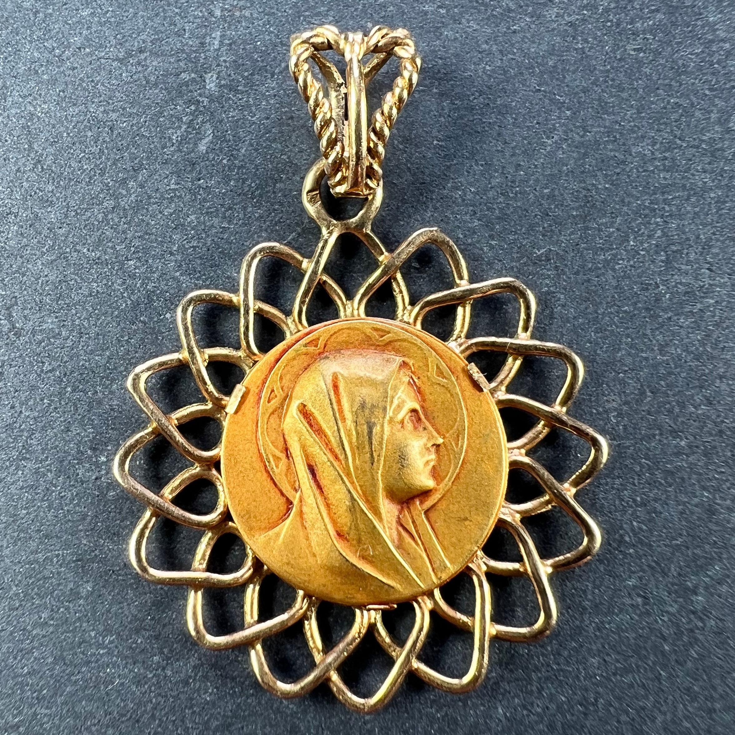 A French 18 karat (18K) yellow gold pendant designed as a round medal depicting the Virgin Mary within a halo within a radiating fretwork gold wire frame. Stamped with the eagle’s head for French manufacture and 18 karat gold, with an unknown