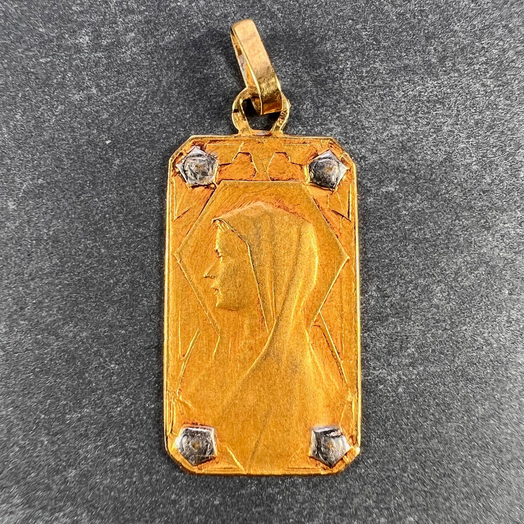 A French 18 karat (18K) yellow gold charm pendant designed as a rectangular medal depicting the Virgin Mary with white gold rosettes to each corner. Stamped with the eagle mark for 18 karat gold and French manufacture with an unknown maker's mark. 