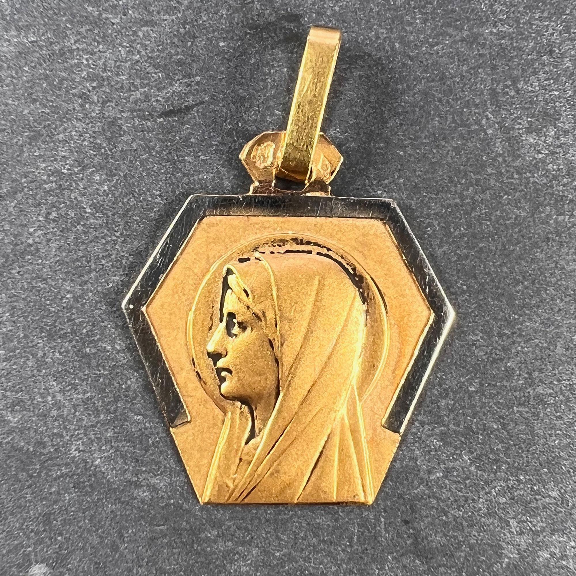 A French 18 karat (18K) yellow and white gold charm pendant designed as an Art Deco shield shaped pendant depicting the Virgin Mary. Stamped with the eagle mark for 18 karat gold and French manufacture.

Dimensions: 1.8 x 1.6 x 0.1 cm (not including