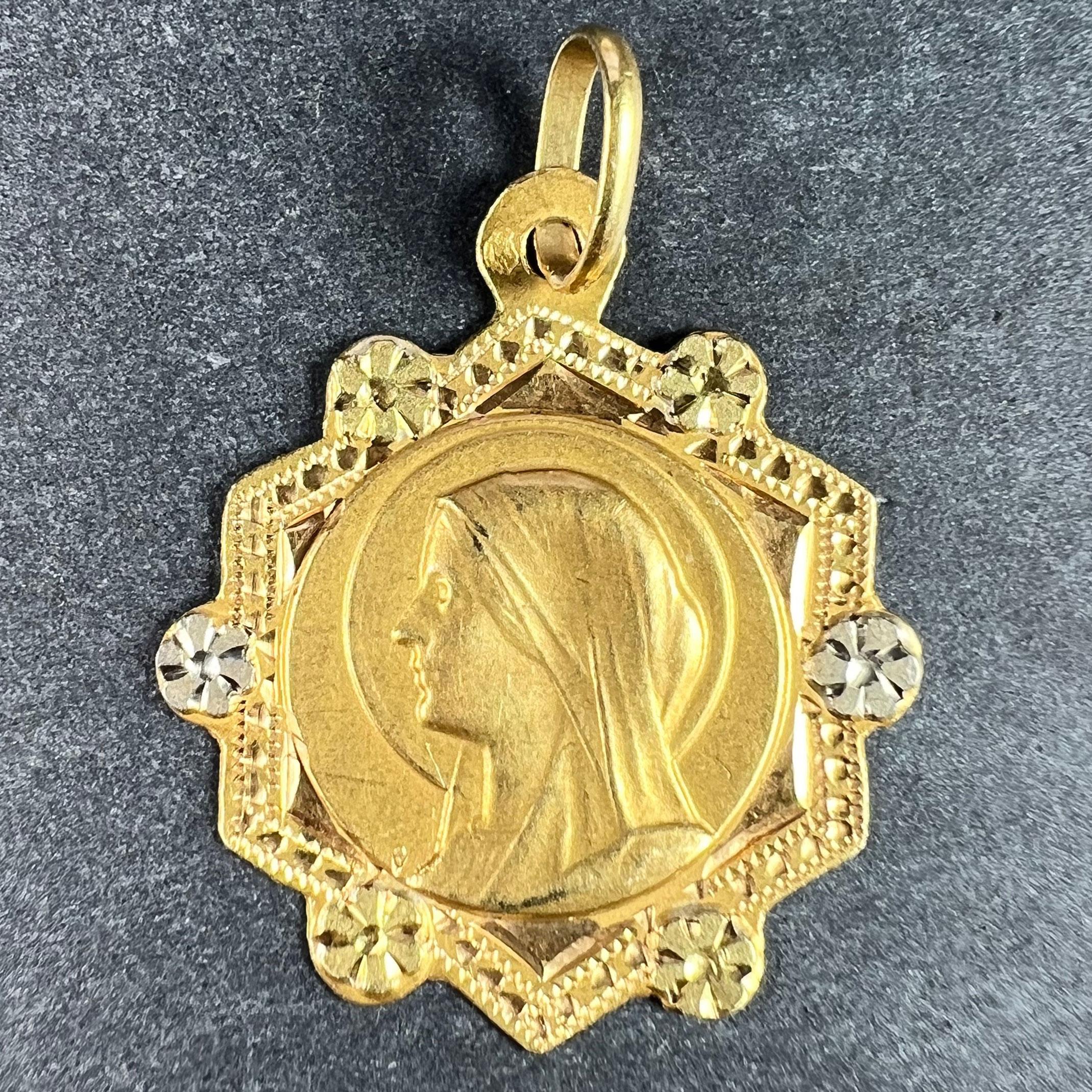 A French 18 karat (18K) yellow gold charm pendant designed as a hexagonal medal depicting the Virgin Mary with alternating rosettes of white and yellow gold to the edges. Engraved to the reverse ‘Anne-Marie Moreau nee le 21 Septembre 1930’. Stamped