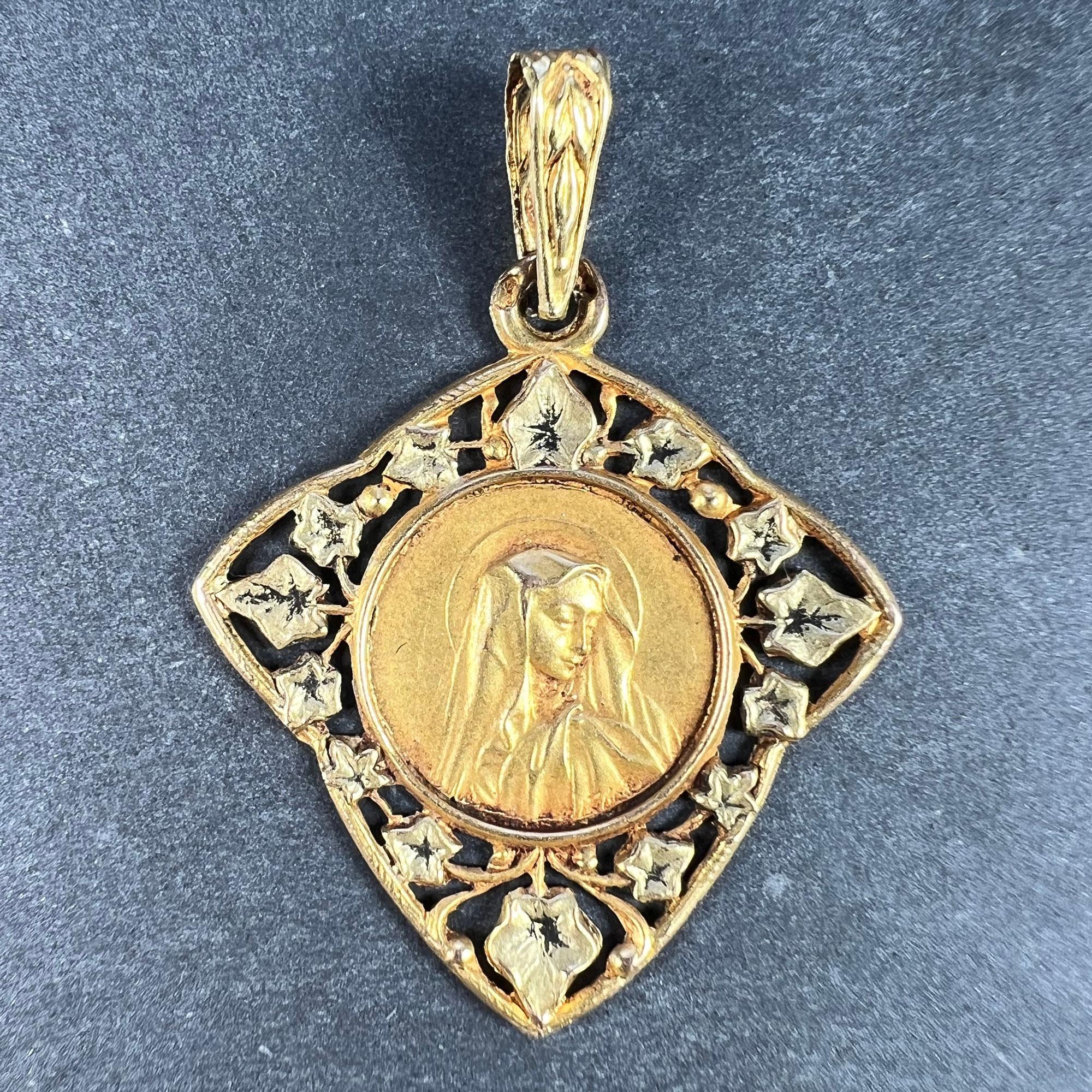 A French 18 karat (18K) yellow gold charm pendant designed as a round medal depicting the Virgin Mary within a pierced frame of ivy leaves symbolising eternal love, the whole shaped as an ivy leaf. Stamped with the eagle's head for French