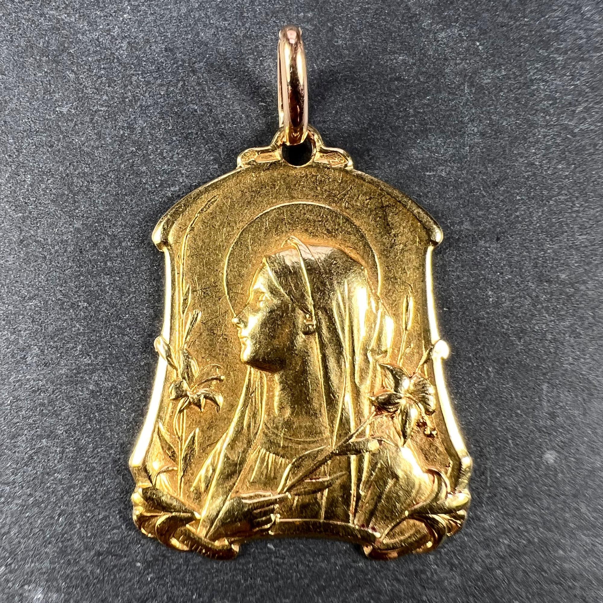 Ein Anhänger aus 18 Karat (18K) Gelbgold in Form einer schildförmigen Medaille, die die Jungfrau Maria umgeben von Lilien darstellt. Unterzeichnet Tairai. Die Rückseite zeigt ein Lilienfeld über dem Monogramm MD mit der Jahreszahl 