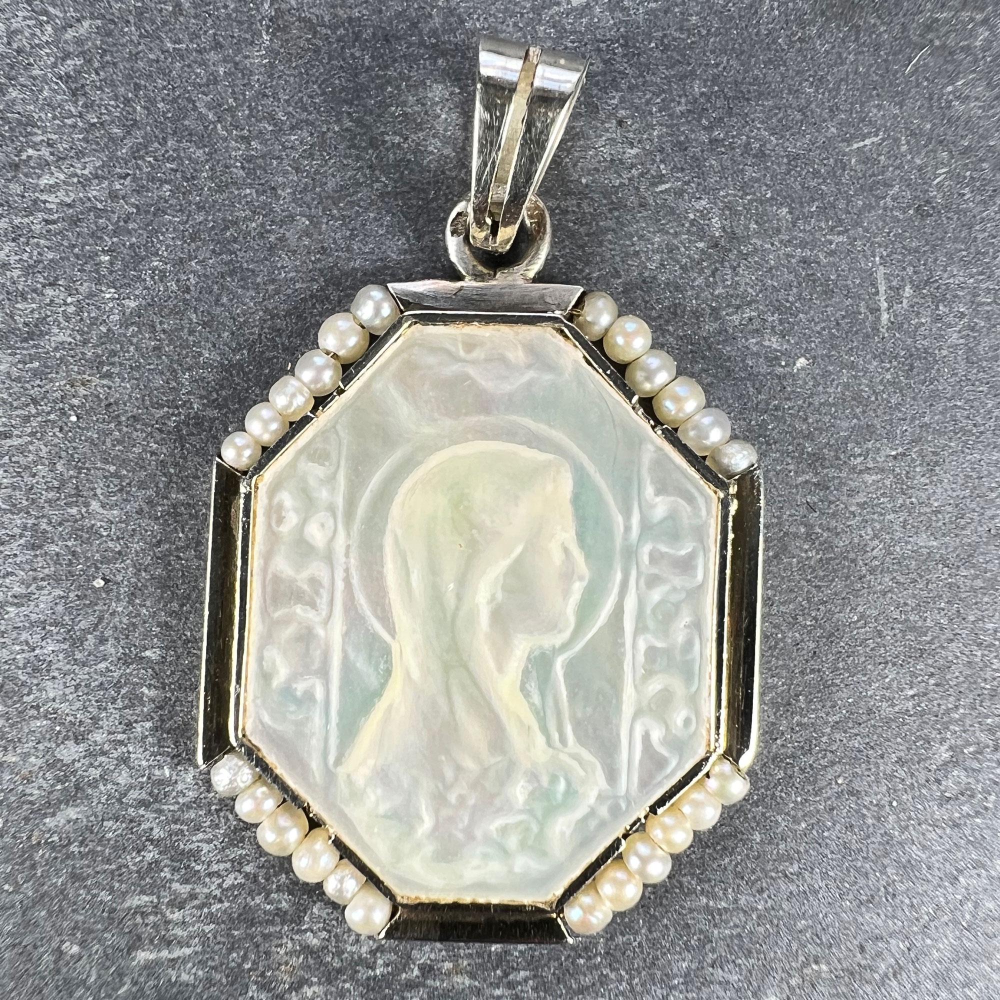 A French 18 karat (18K) white gold charm pendant designed as a mother-of-pearl medal depicting the Virgin Mary surrounded by 24natural seed pearls. Stamped with the eagle mark for 18 karat gold and French manufacture and an unknown maker’s