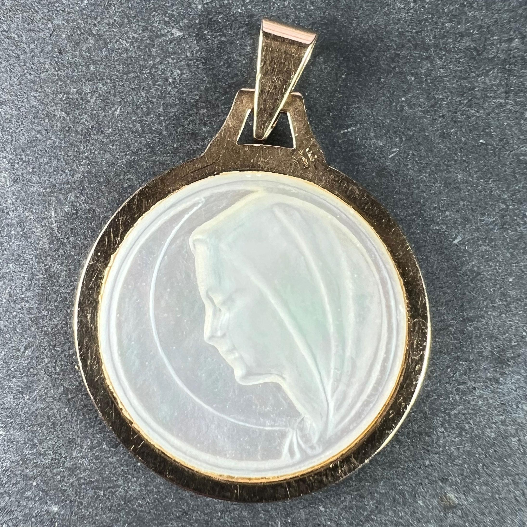 An 18 karat (18K) yellow gold charm pendant set with mother of pearl depicting the Virgin Mary in profile. Stamped with the eagle mark for 18 karat gold and French manufacture
 
Dimensions: 2.2 x 1.9 x 0.25 cm (not including jump ring)
Weight: 1.93