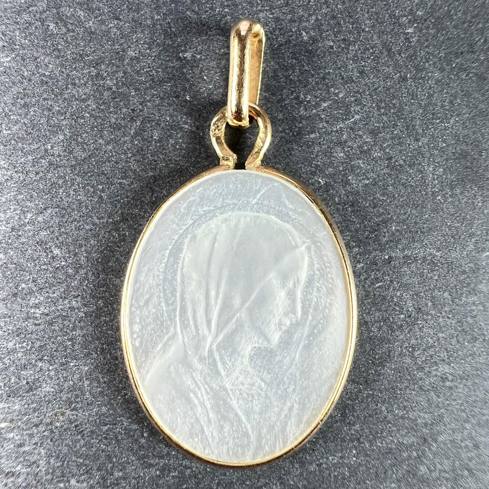 An 18 karat (18K) yellow gold charm pendant set with mother of pearl depicting the Virgin Mary in profile. Stamped with the eagle mark for 18 karat gold and French manufacture along with an unknown maker's mark.
 
Dimensions: 2.2 x 1.4 x 0.15 cm