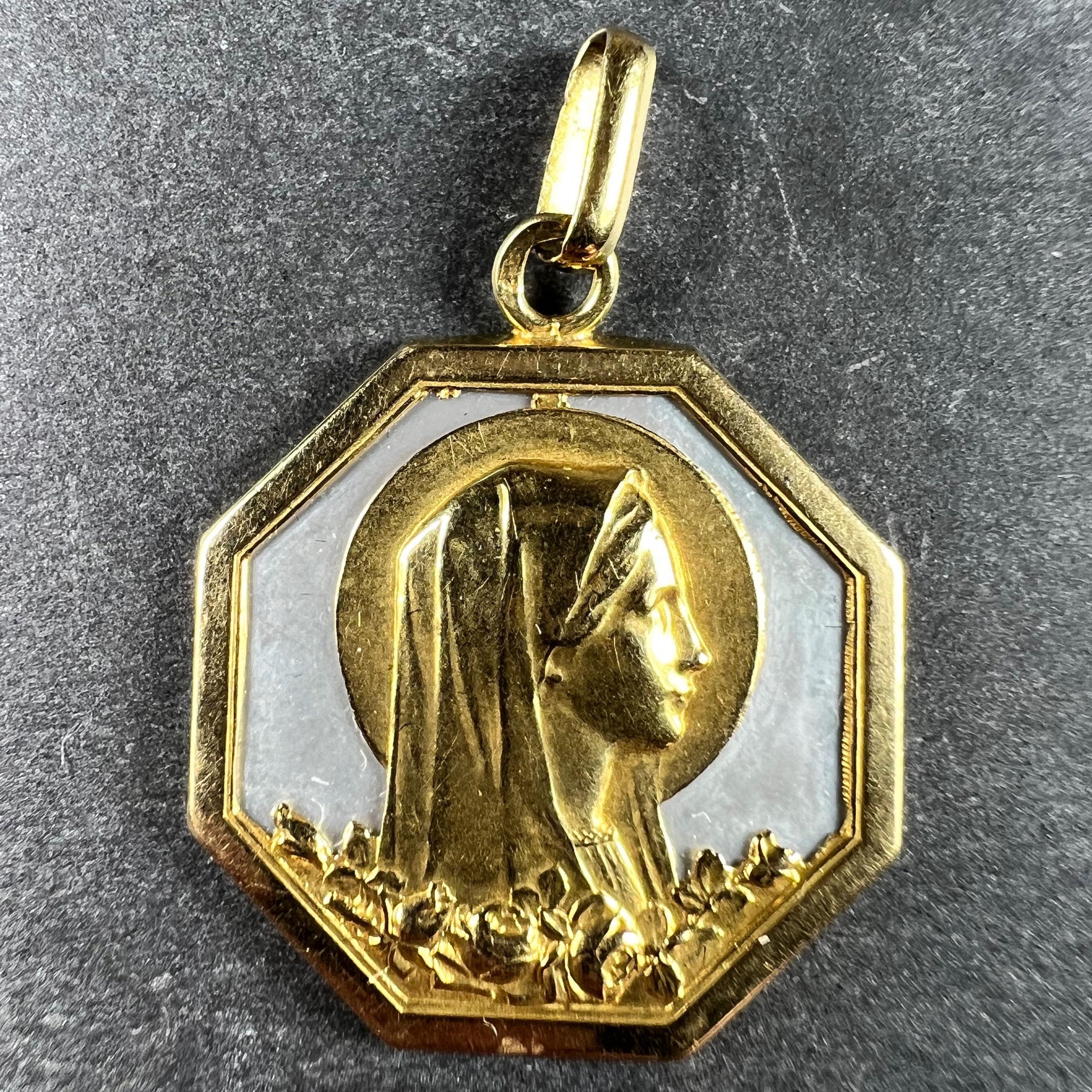 An 18 karat (18K) yellow gold charm pendant set with mother of pearl depicting the Virgin Mary with a halo above a field of roses. Engraved to the reverse with a monogram for GM / MG and the date 18-5-36. Stamped with the owl mark for 18 karat gold