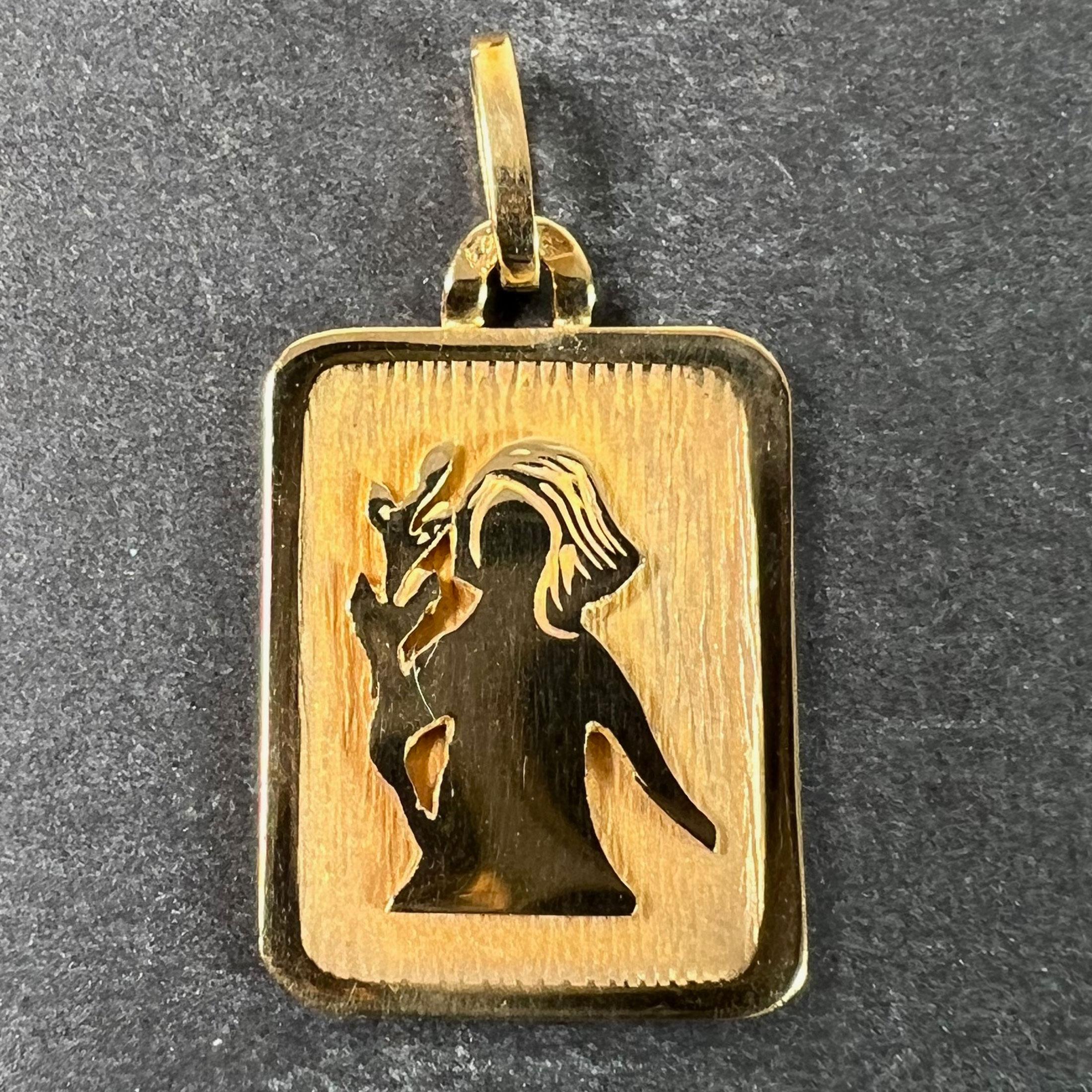 A French 18 karat (18K) yellow gold charm pendant designed as a rectangular medal with an engraved recess depicting a woman holding a branch representing the zodiac star sign of Virgo. Stamped with the eagle’s head for French manufacture and 18