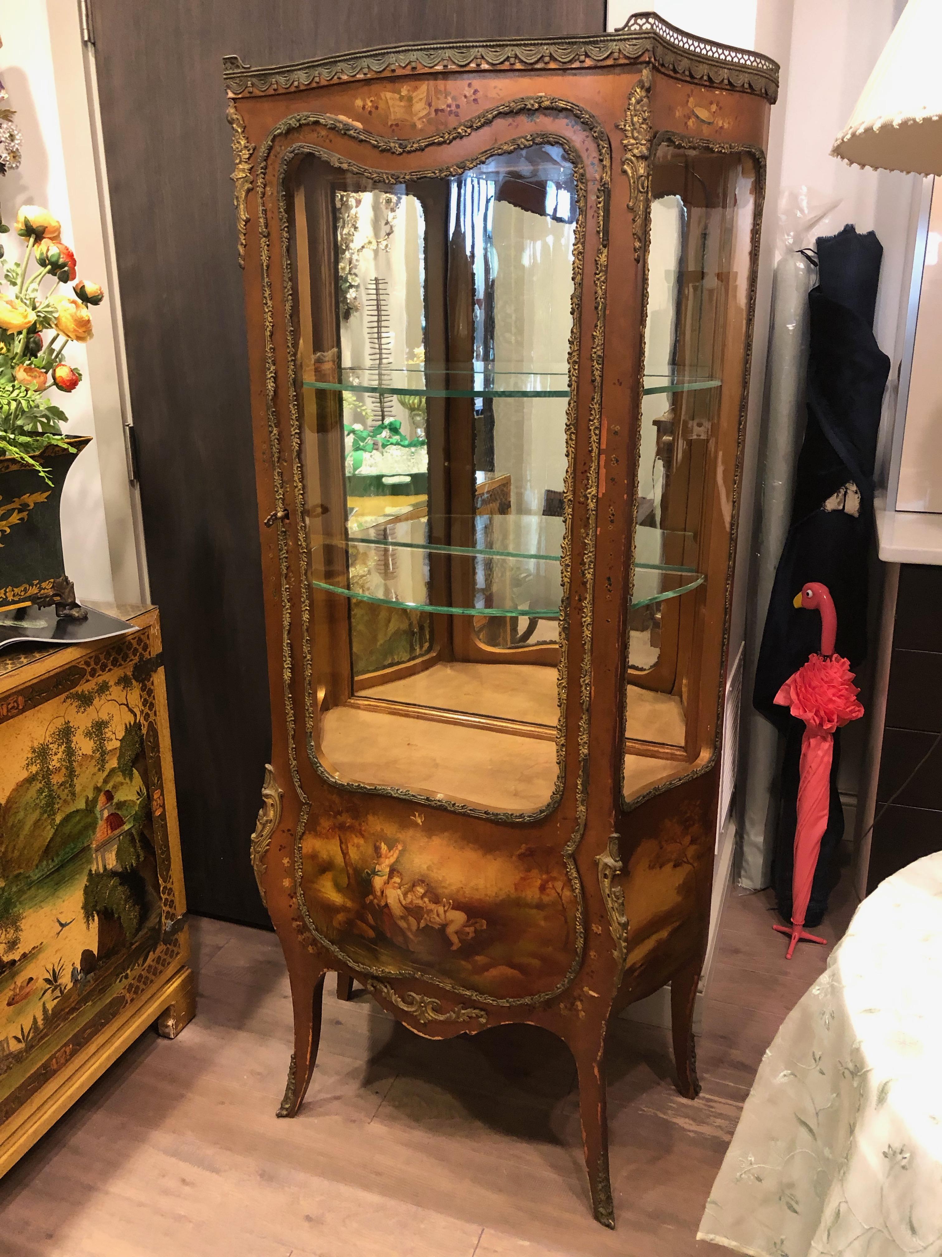 French mounted Vitrine Bombay front and sides curved glass door hand painted scenes to the sides and front having 2 glass shelfs and original key Also having a mirrored back to show off displayed items and electric with light.
