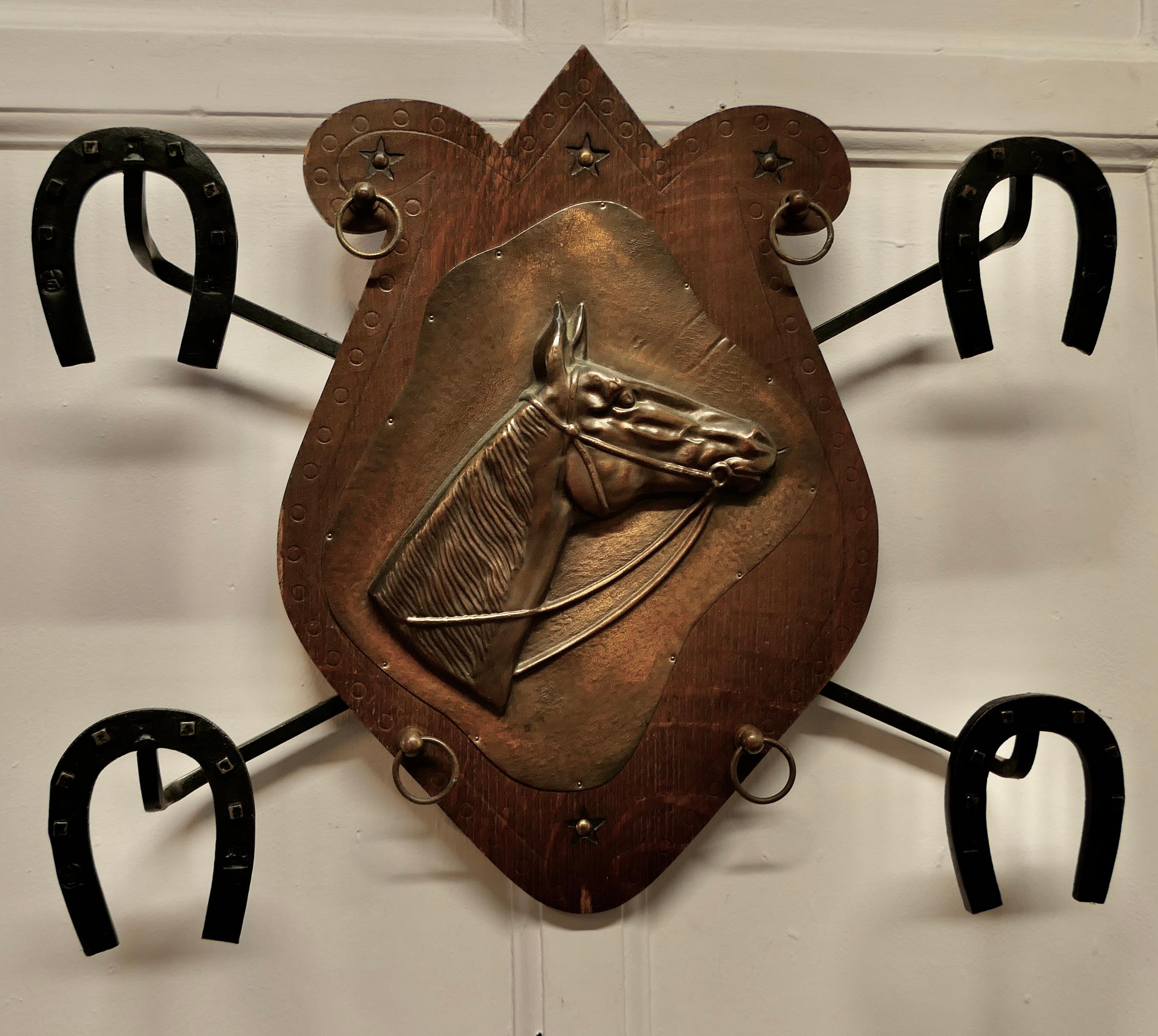 Französische Wandgarderobe für Mäntel und Tack zum Thema Reiten 

Dies ist ein attraktives Wandregal mit 4 Aufhängern, diese sind aus Eisen und in Form von Horse Shoes und in der Mitte gibt es eine geschlagene Kupferplakette eines Pferdekopfes
Ein