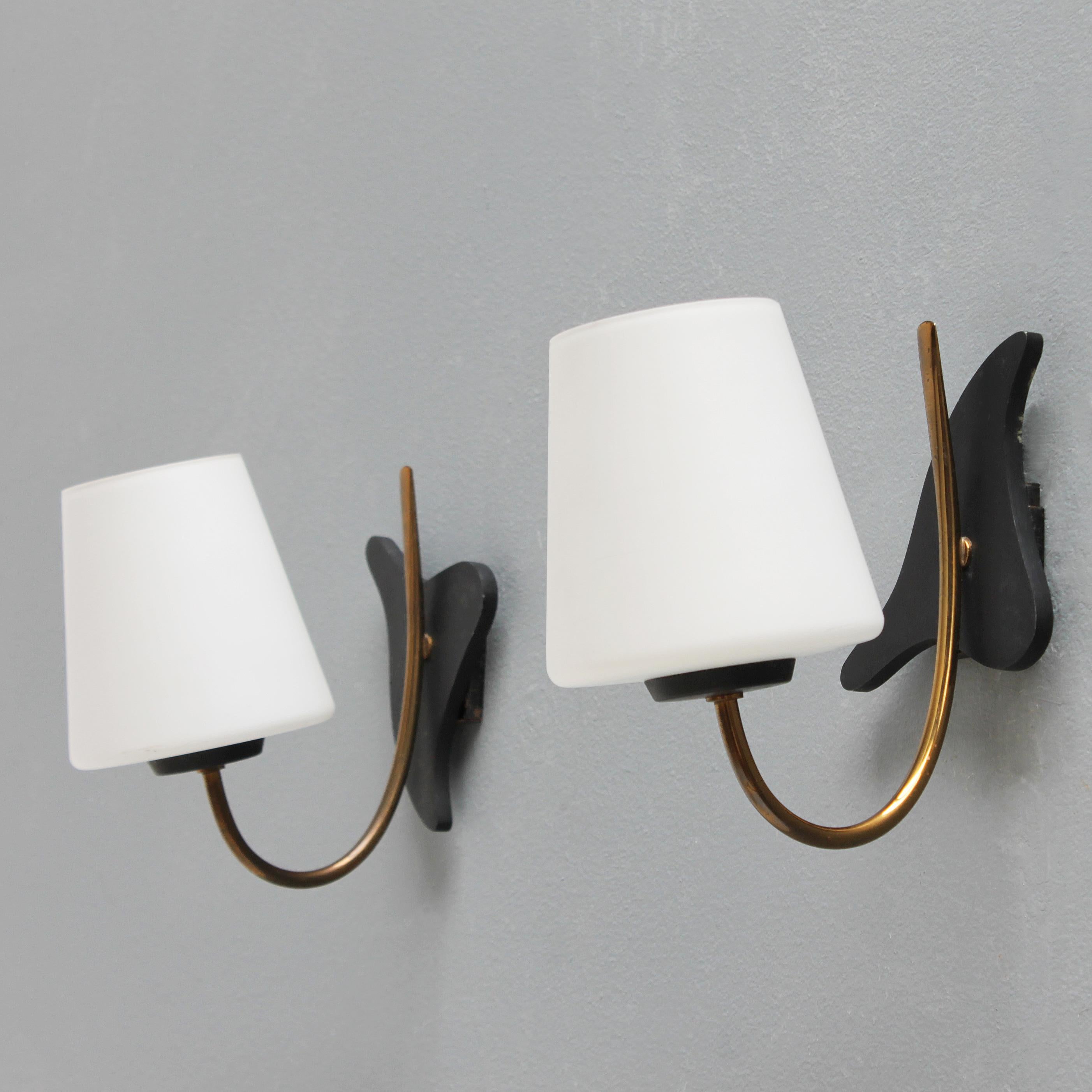 Pair of brass wall lights with white opaline glass and matt black wall plates. French by Maison Lunel from the 1950s. Beautiful condition.
The biomorphe black wall plates can be rotated in any position: symmetrical or vice versa.
Each light has a