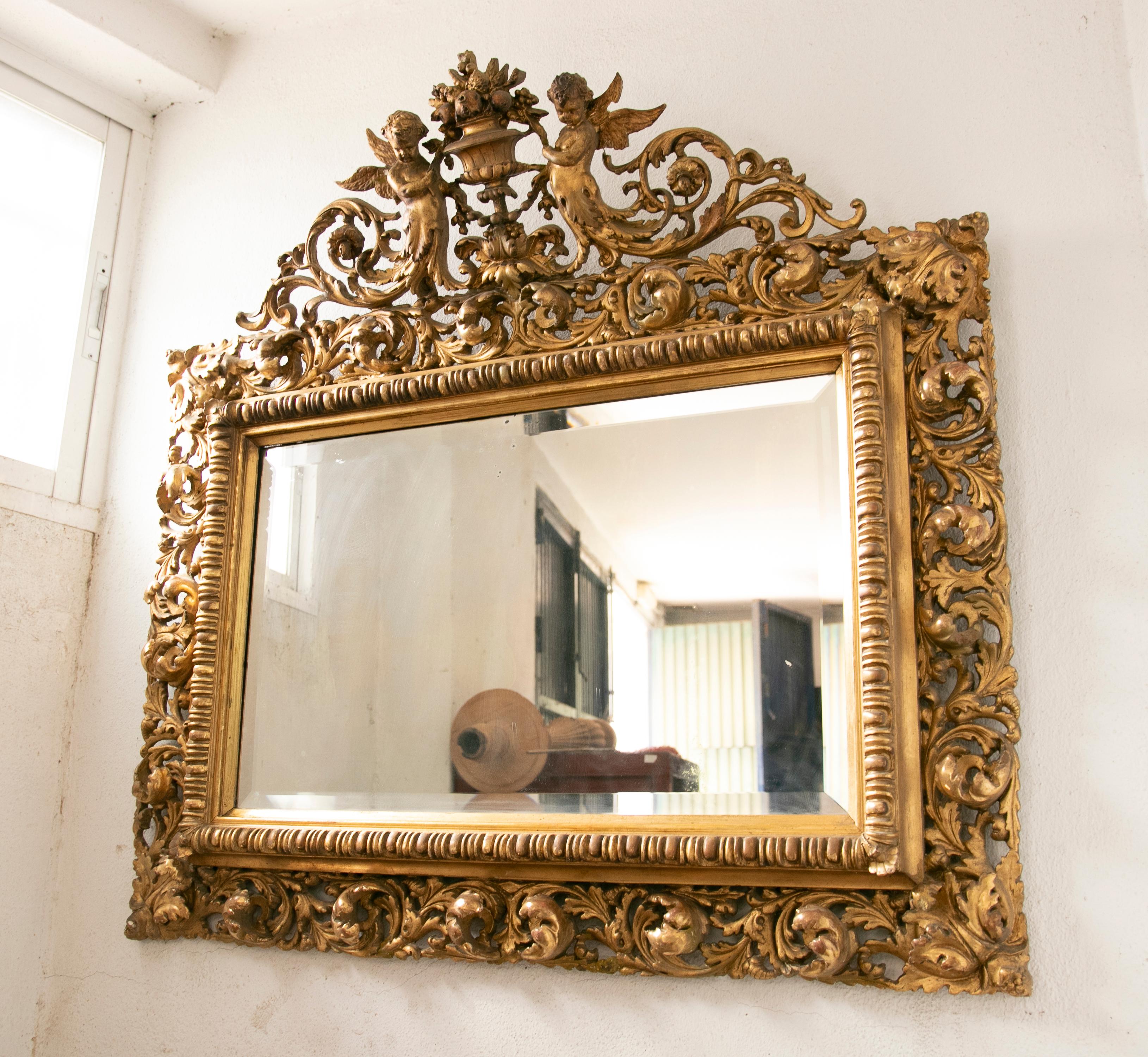 French wall mirror in gilded wood with flowers and cherubs decoration.