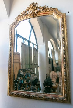 French Wall Mirror in Gilded Wood with the Coping Top Decorated with Instruments