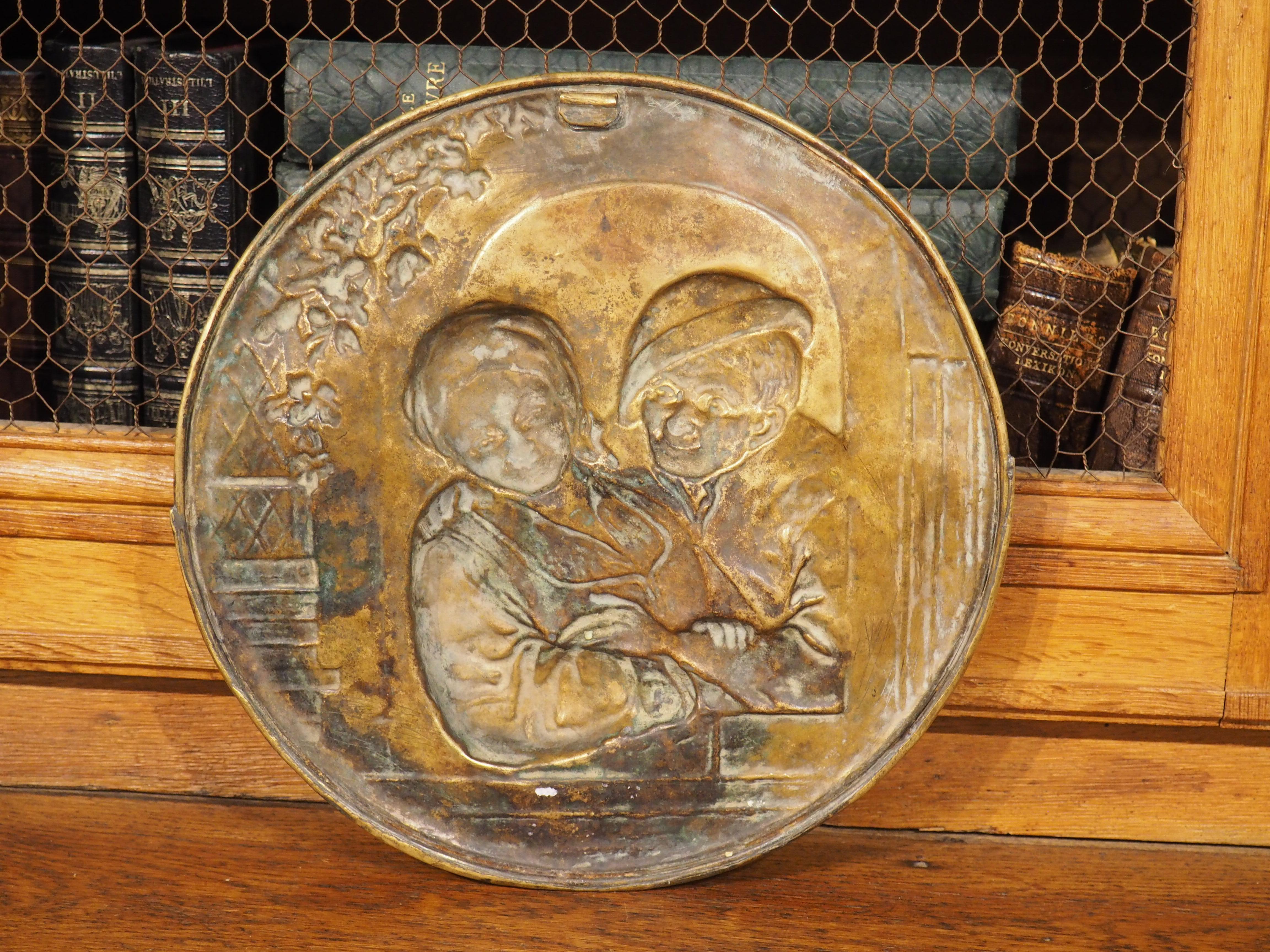 Delicately worked from the verso side in a technique known as repousse, this French brass decorative accessory is from circa 1890. The wall-mounted circular plaque would have once served as a letter pocket, allowing hand-delivered mail to be placed