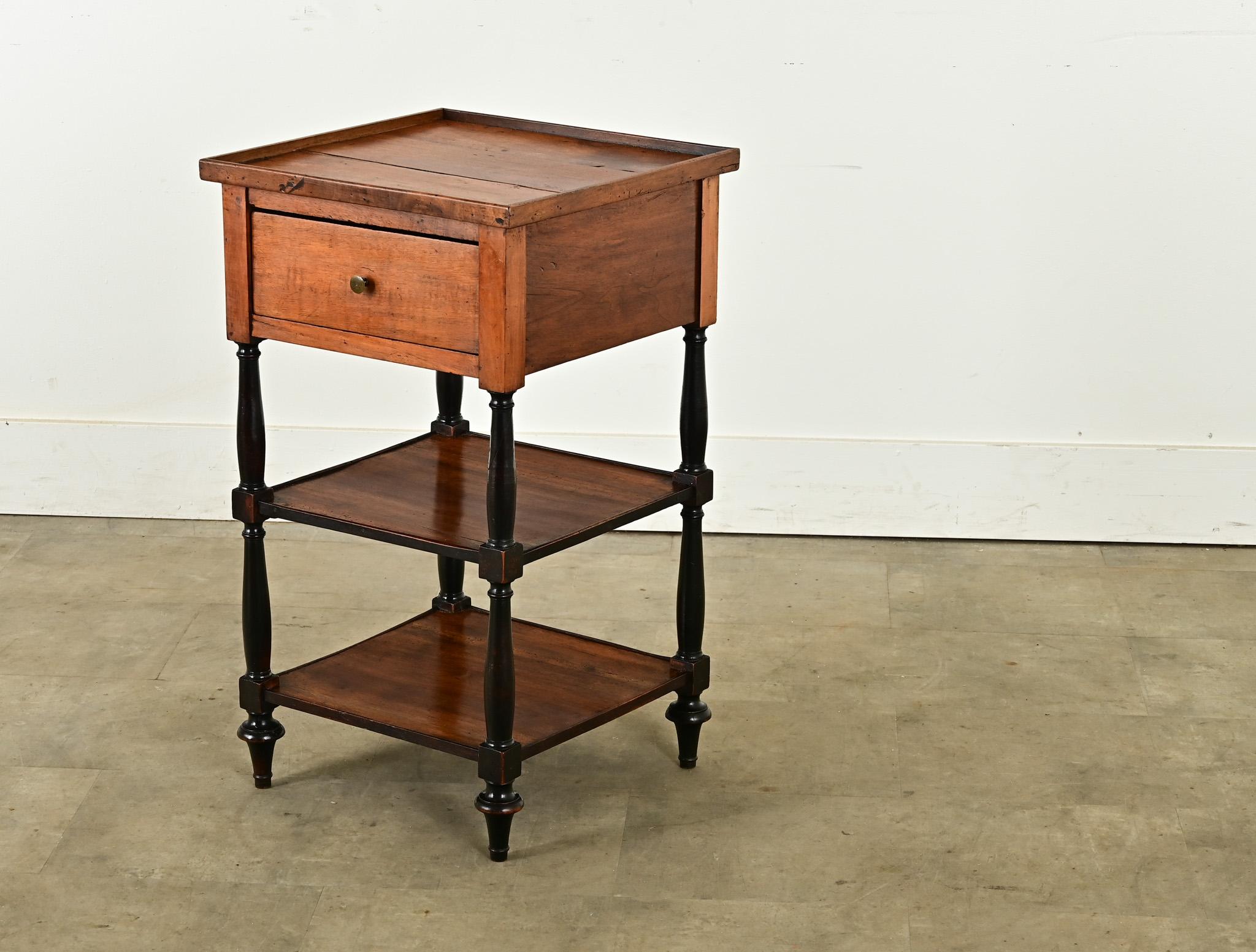 A simple yet distinct walnut etagere with ebonized legs from France, circa 1870. The top showcases the characteristic grain patterns of walnut and features a thin lip on all four sides. A single drawer is housed in the apron and easily slides out