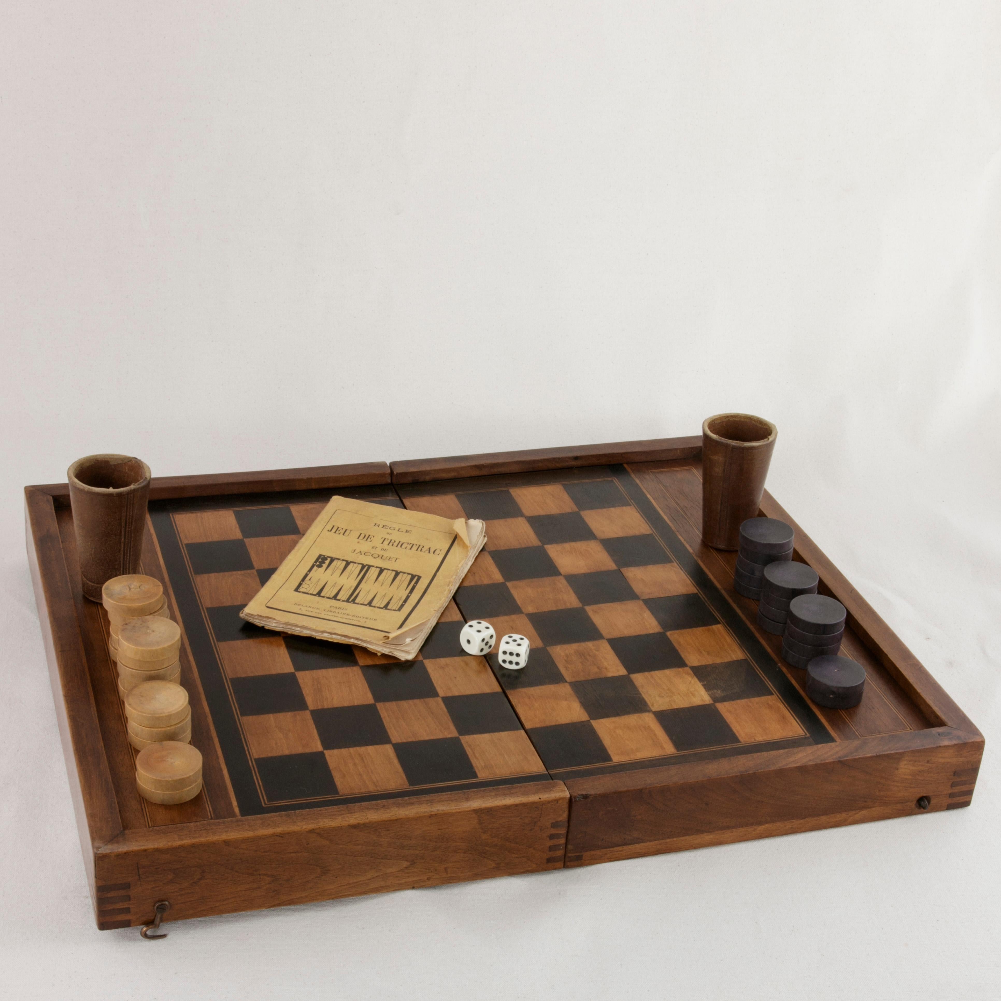 This French walnut marquetry folding game box from the turn of the twentieth century is for both checkers and backgammon. It is finely constructed with dovetailed corners, inset hinges, and a locking brass hook on each side. The checker board side