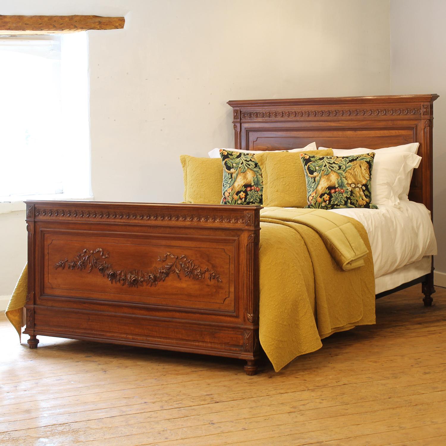 Fina cama antigua francesa de principios del siglo XX, de nogal, con un decorativo panel tallado que representa una guirnalda de rosas en el piecero.

Esta cama admite un conjunto de somier y colchón US Queen Size (o UK King Size) de 1,80 m de
