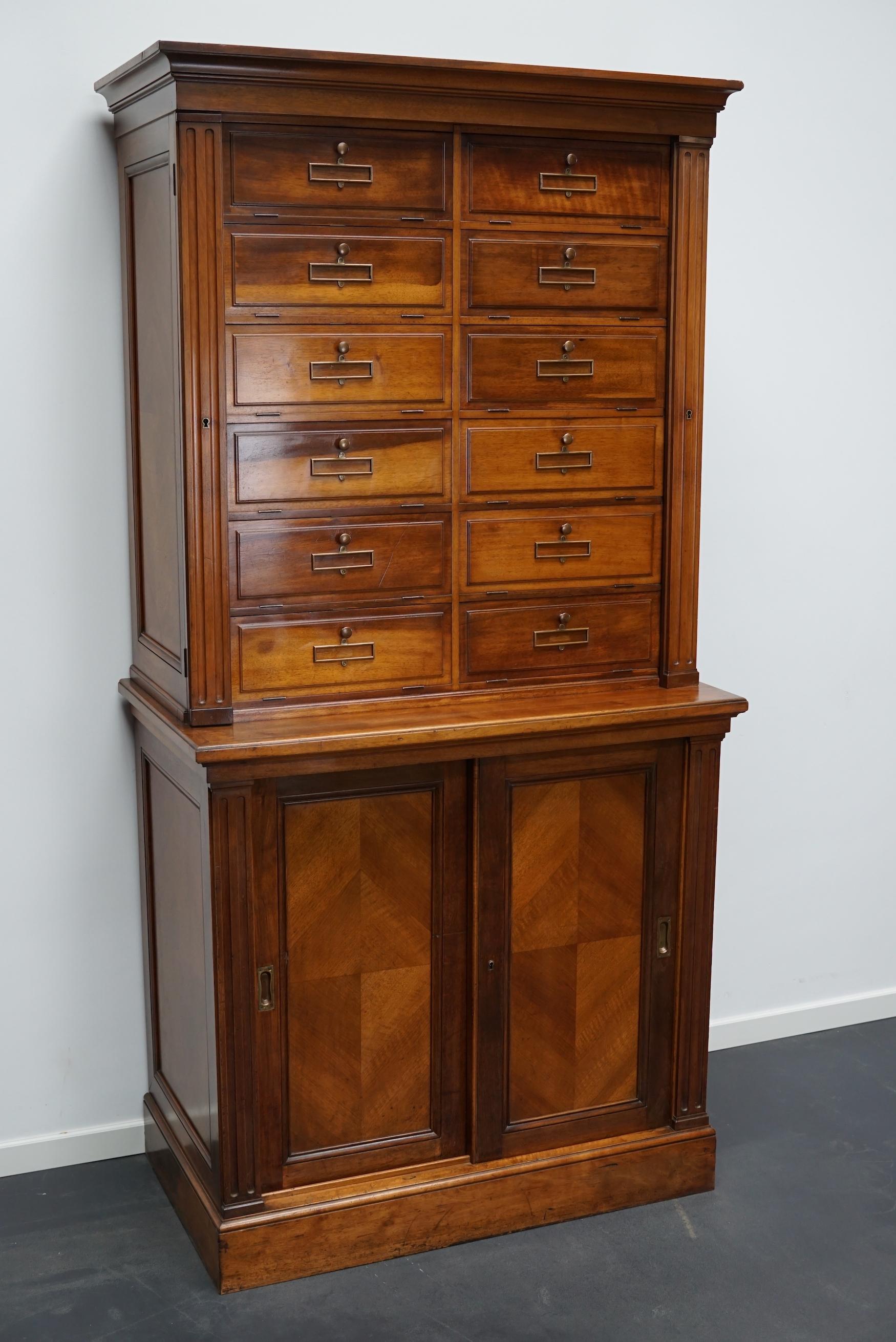 This filing cabinet was made around the 1920s in France. It is made from solid walnut with drop down doors, two sliding doors and brass hardware. It was used in Banque de France in the city Rouen.