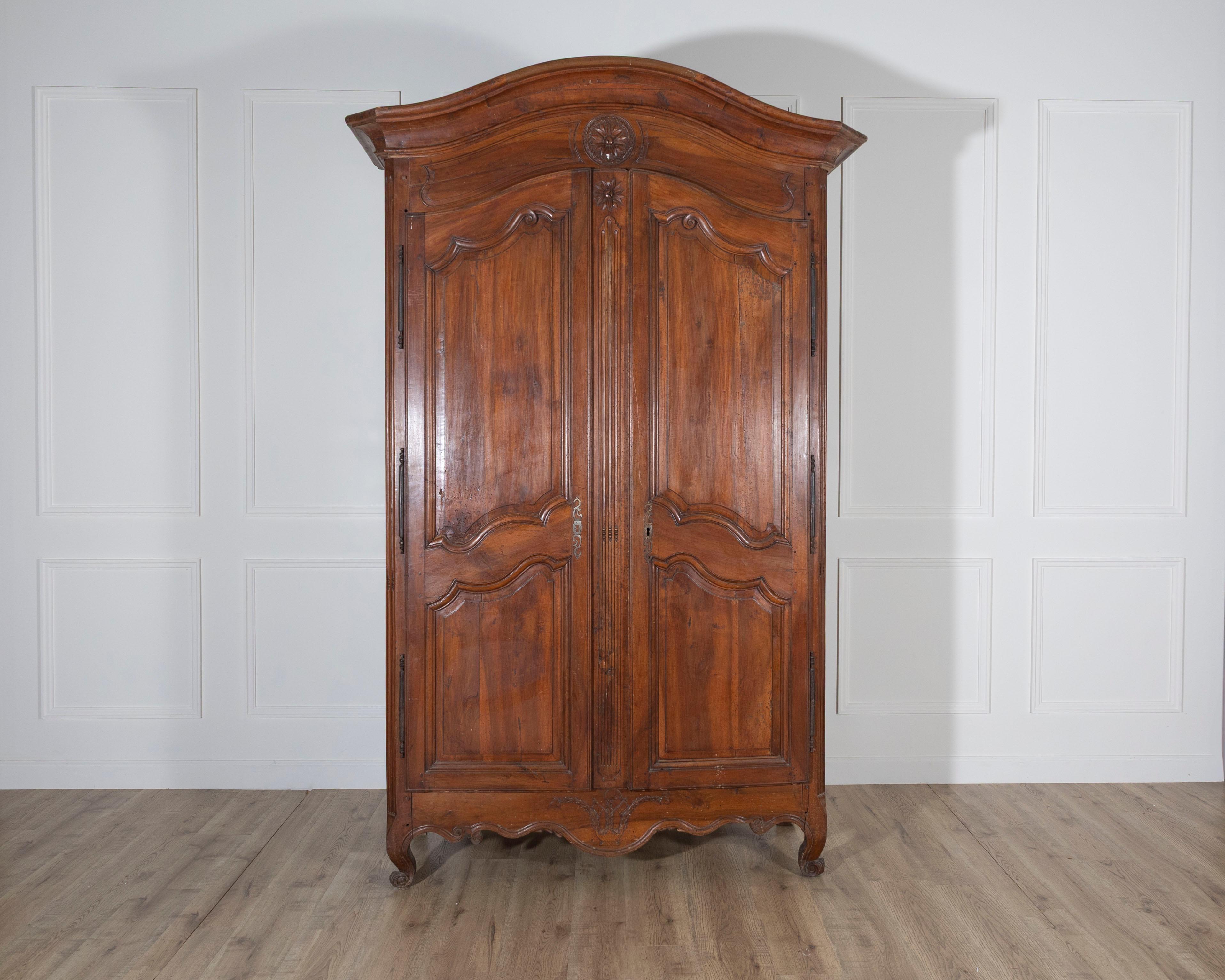 An elegant French walnut armoire linen cupboard dating to the Transition period between Louis XV and Louis XVI, late 18th century. The piece is distinguished by its two paneled walnut doors, each with sinuously carved moldings that reflect the