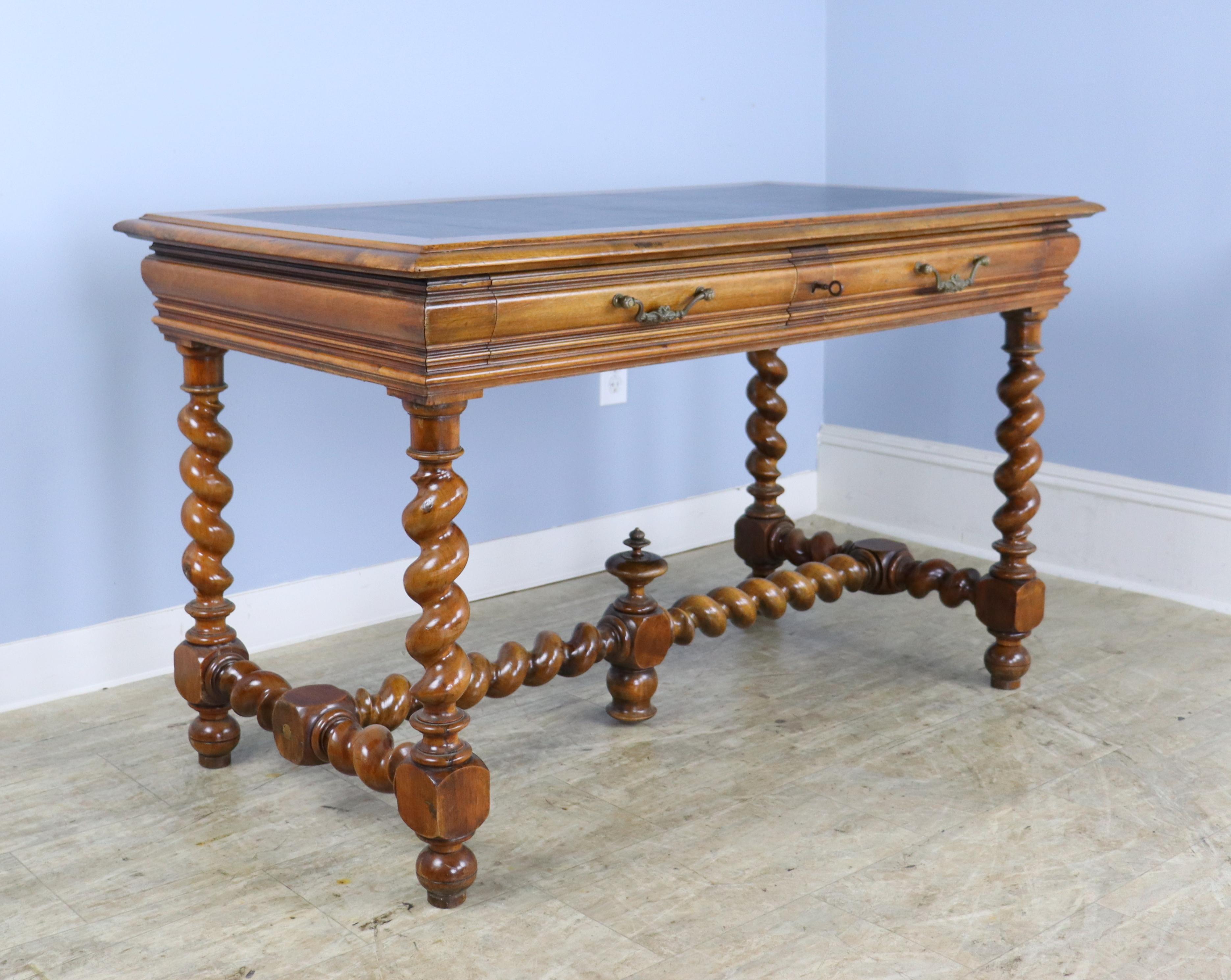 A handsome leather topped desk or writing table with spectacular barley twist legs and support, complete with a regal finial at the center of the trestle.  The walnut on this piece is in good condition, with great color and a fine glossy patina. 