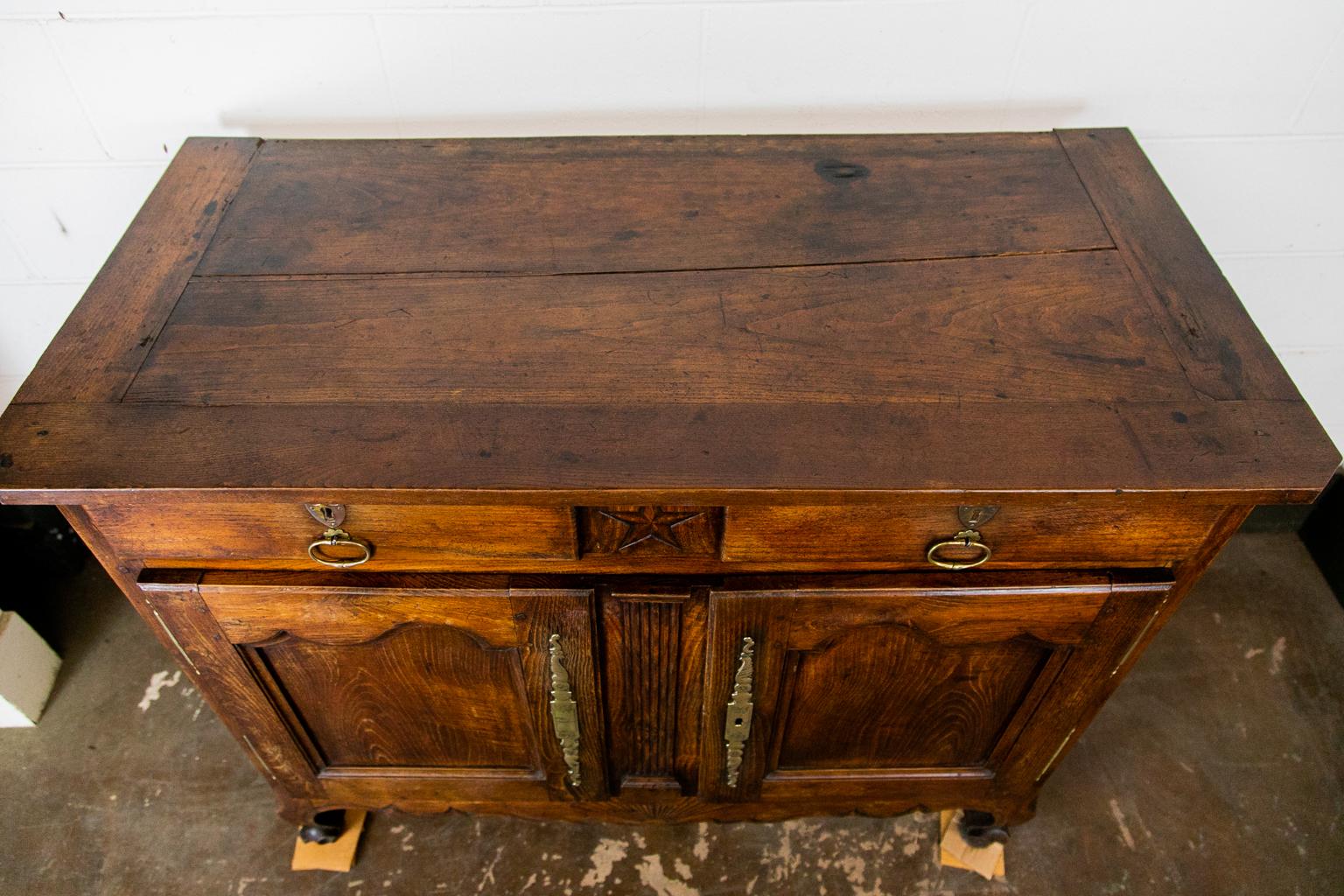 The top of this buffet has a 1/8 inch separation on the top. There are four inch wide breadboard ends. There is an encised carved star between the two drawers. A fluted pilaster divides the two doors but is actually attached to the left end door.