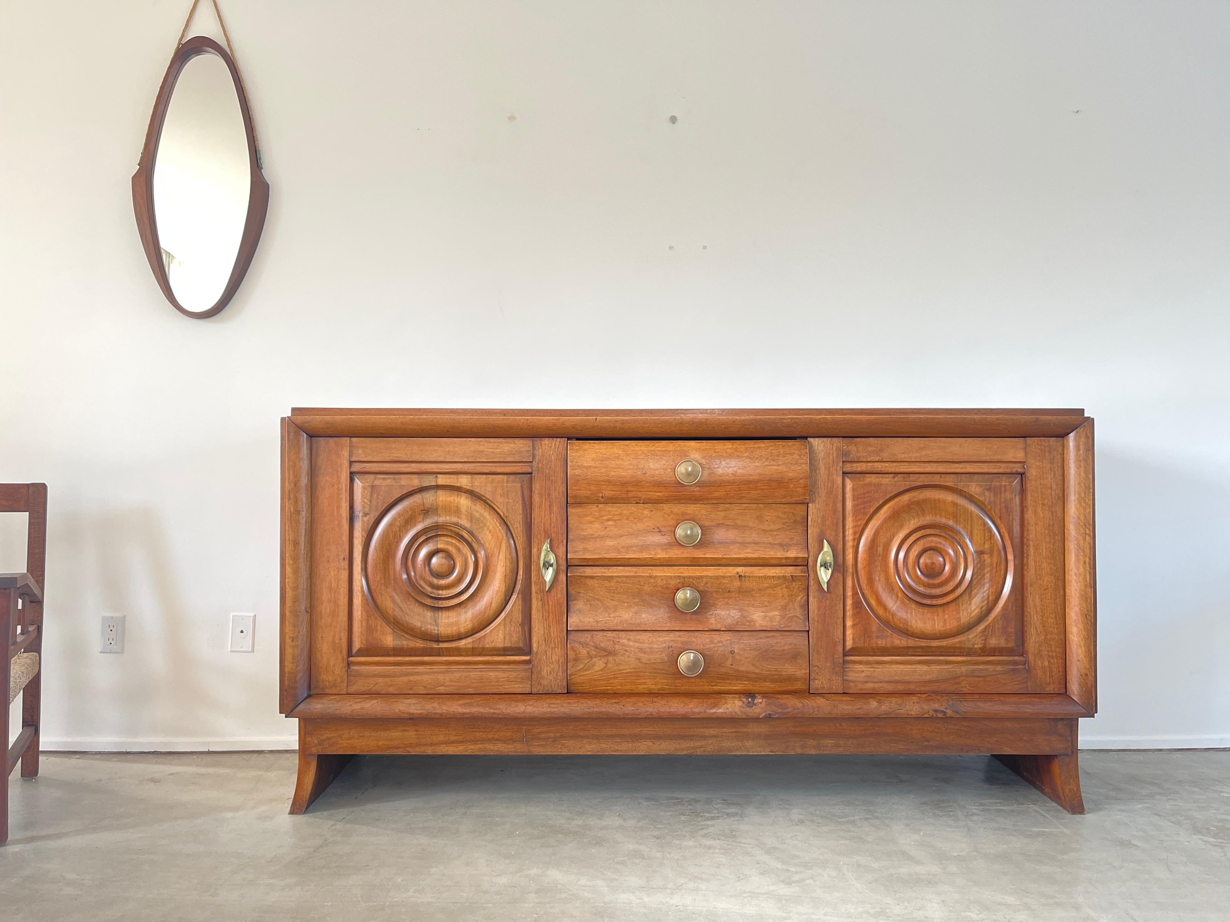 1930's French walnut cabinet with concentric circle carvings on each door and ornate detail throughout. 
Original brass hardware - open shelving with center drawers
Original finish with wonderful patina.