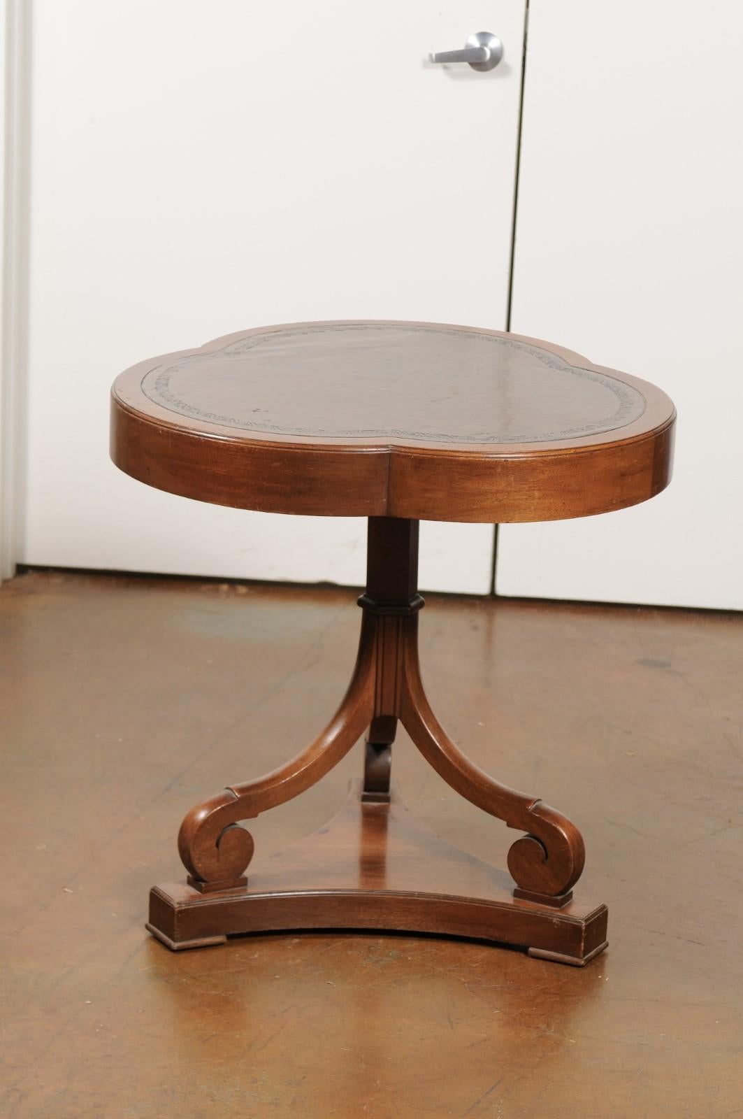 A French walnut clover leaf accent table from the 19th century with tooled leather top and scrolling base. This pretty French table features an exquisite clover leaf shaped top, fitted with brown tooled leather. This unusual top is raised on a