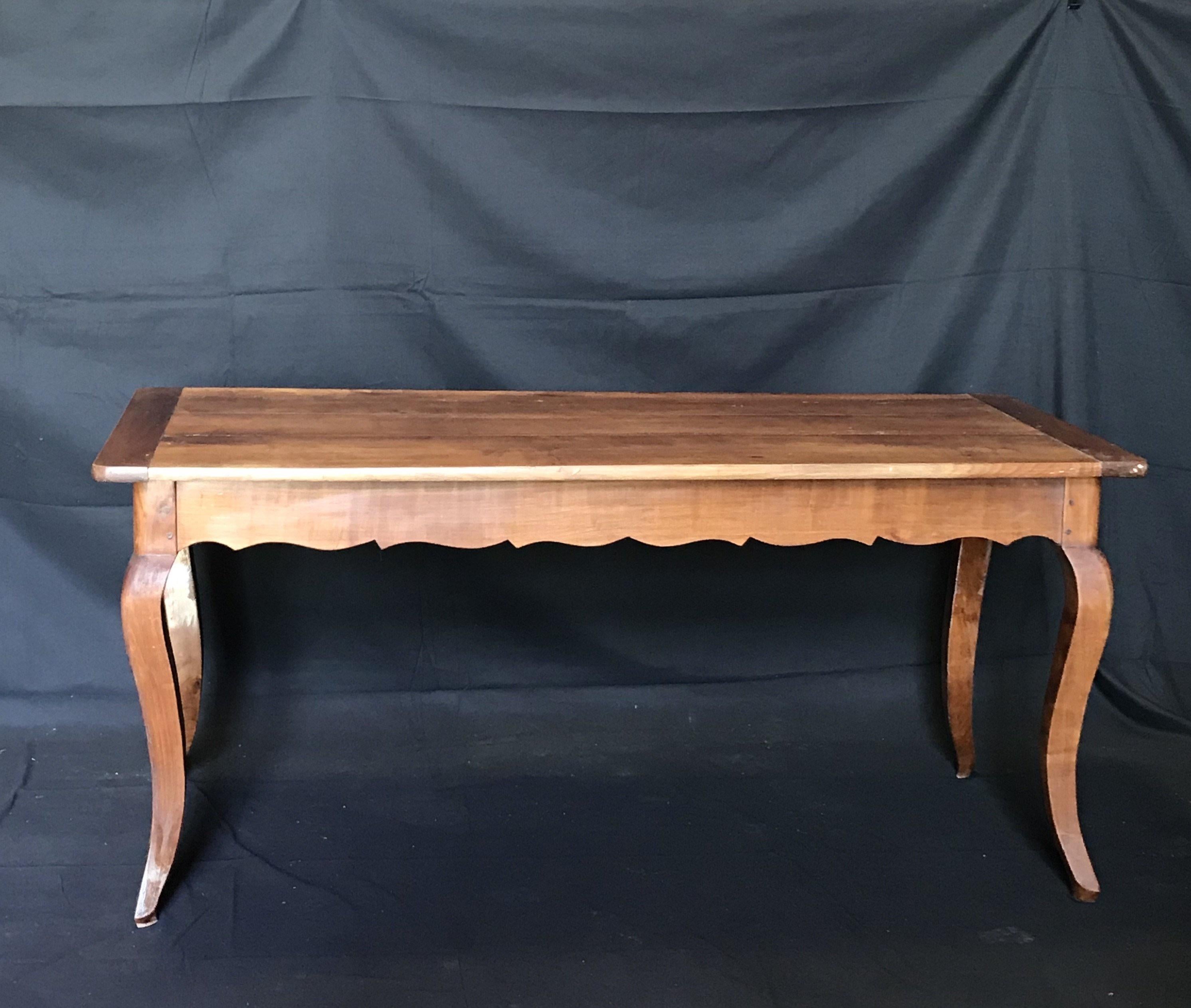 19th century farm table from France having banded top and lovely scalloped apron, supported on hand-turned cabriole legs with molded edges. Could also serve as a large long desk.
Measure: H skirt 24” 
 #5209.