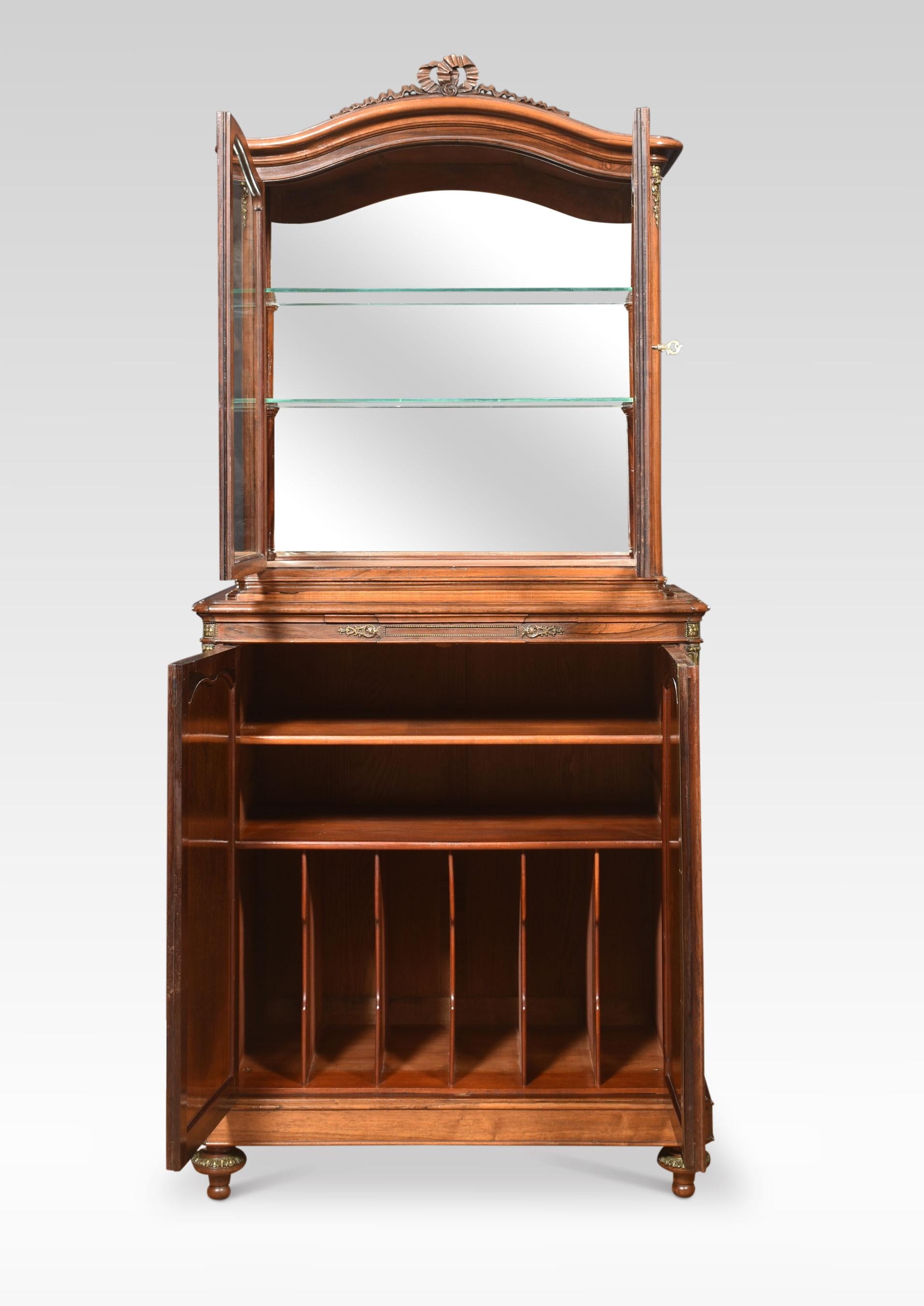 French walnut cabinet, the shaped top with central carved ribbon detail above a pair of glazed doors opening to reveal mirrored back and two glazed shelves. To the base section fitted with pull out velvet lined slide having cupboard doors below with