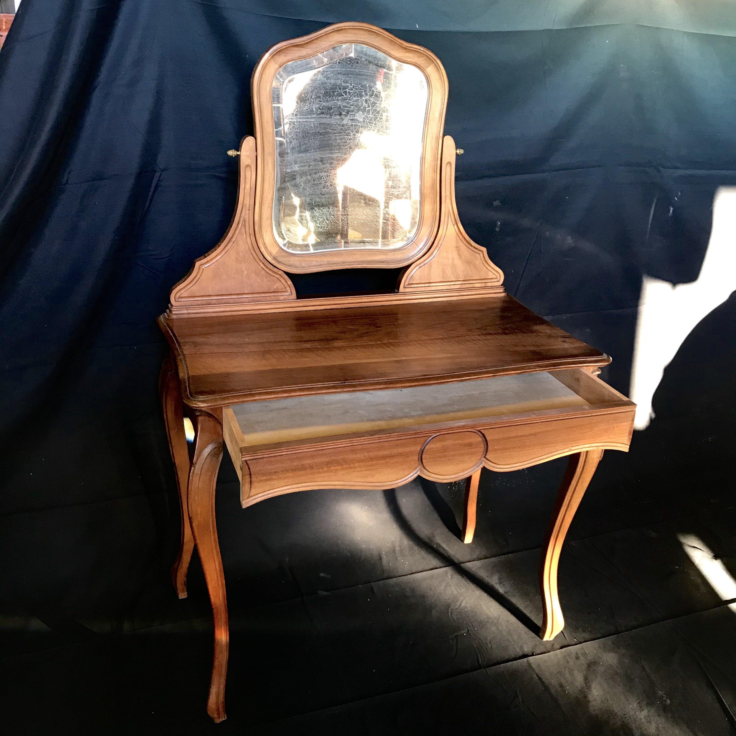 Beautiful French walnut dressing table or vanity with beveled mirror - bought in the South of France. Single drawer having scalloped bottom and handsome circle decoration and elegant cabriole legs.
 
 Measures: H desk top 30” H skirt 24.5” 
#4337.