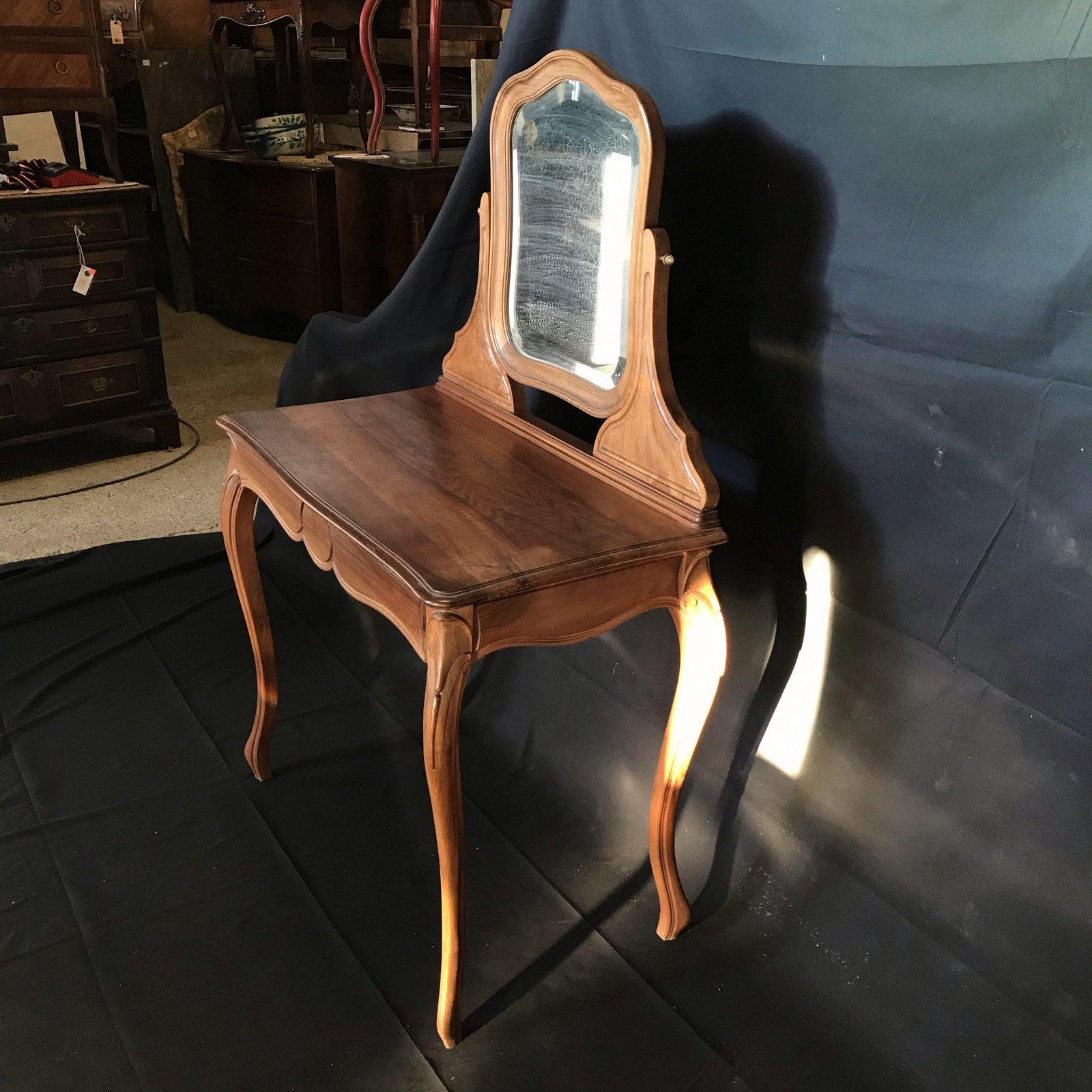 Beautiful French walnut dressing table or vanity with beveled mirror, bought in the South of France. Single drawer having scalloped bottom and handsome circle decoration and elegant cabriole legs.

Measures: H desk top 30”, H skirt 24.5” 
#4337.