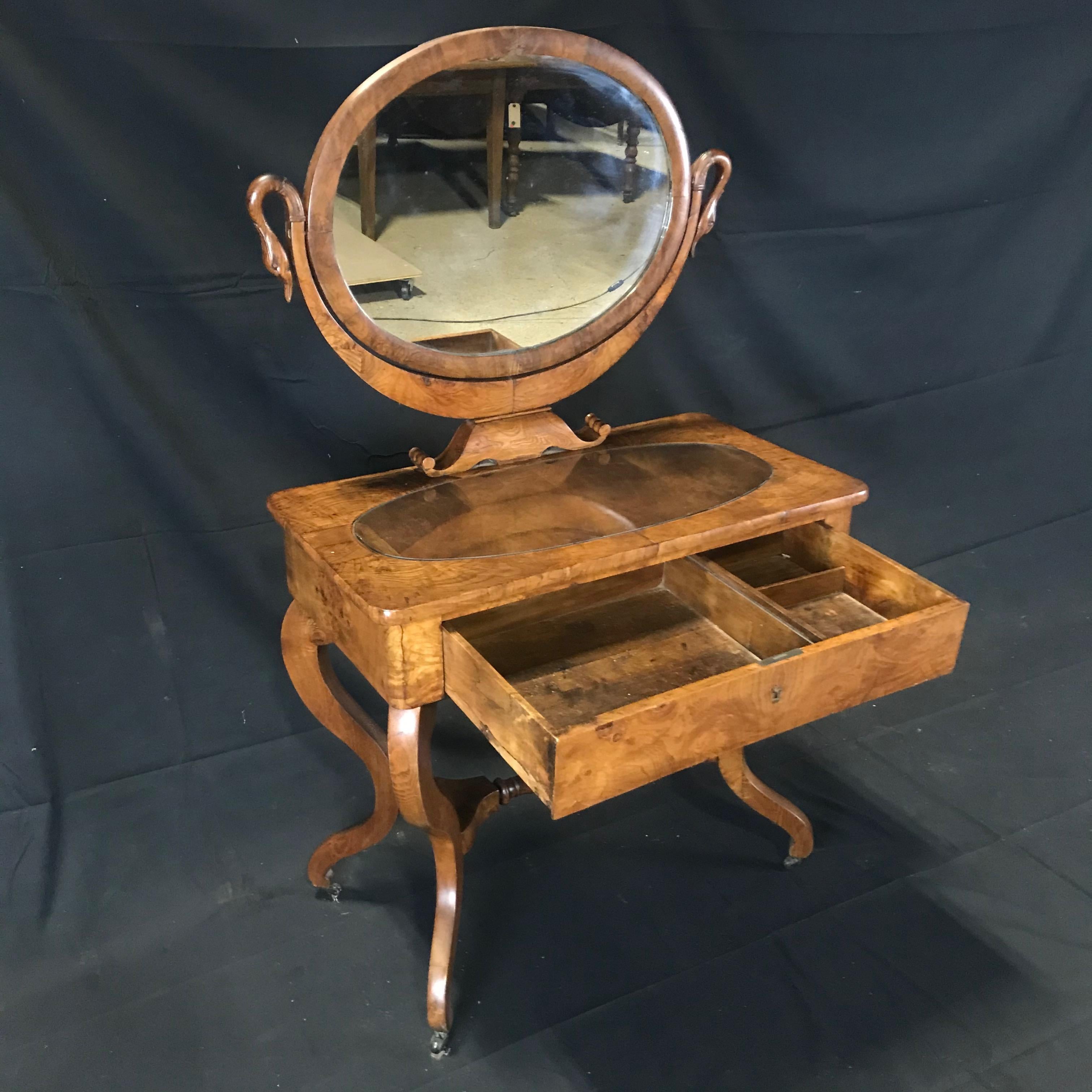 Beautiful French dressing table with mirror in carved walnut with elegant swan neck support uprights. On the sides the mirror is supported by two arms carved in the wood in the shape of a swan. Under the mirror a handy drawer for storing toiletries