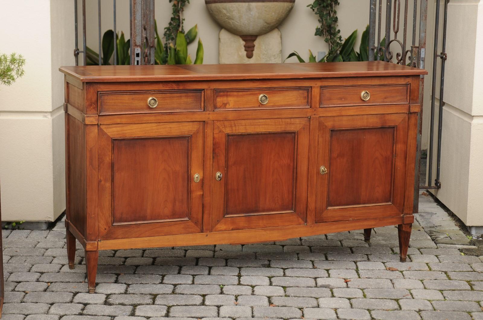 A French walnut three drawers over three doors enfilade from the turn of the century, raised on tapered legs. Born during the turn of the 19th to the 20th century, this French walnut enfilade features a rectangular planked top, sitting above three