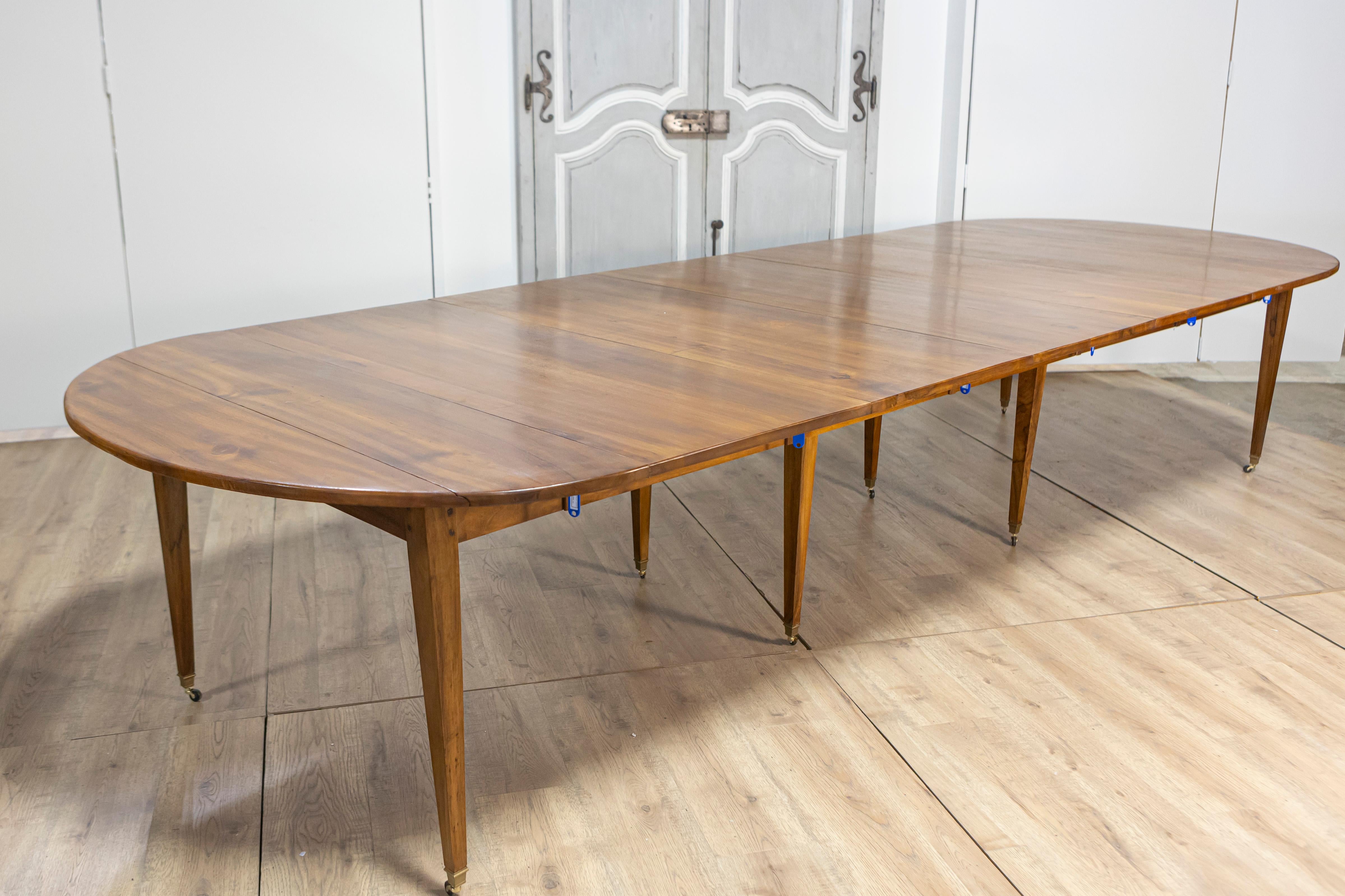 Table de salle à manger ovale à rallonge en noyer français du 20e siècle, avec cinq feuilles, pieds fuselés et roulettes. Cette table à manger ovale à rallonge en noyer français du 20e siècle allie magistralement l'artisanat historique à la