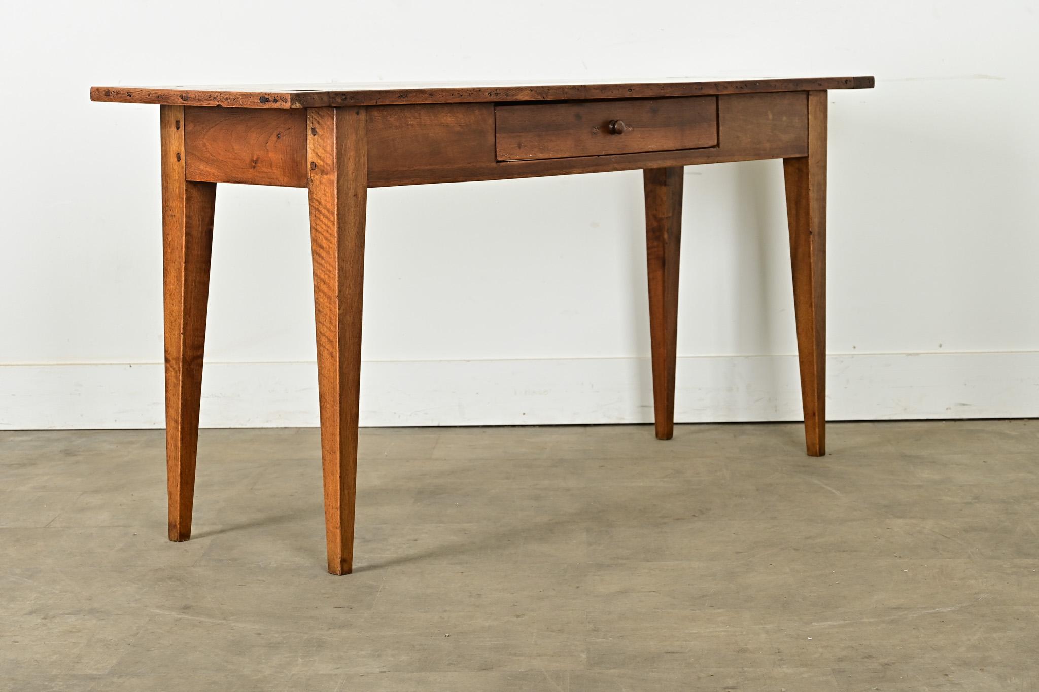A French country house server from circa 1850 with a lovely patina in the walnut planks. The top surface is arranged in a breadboard formation and held with square peg joinery. A single drawer at the center of the apron opens with a turned wood knob
