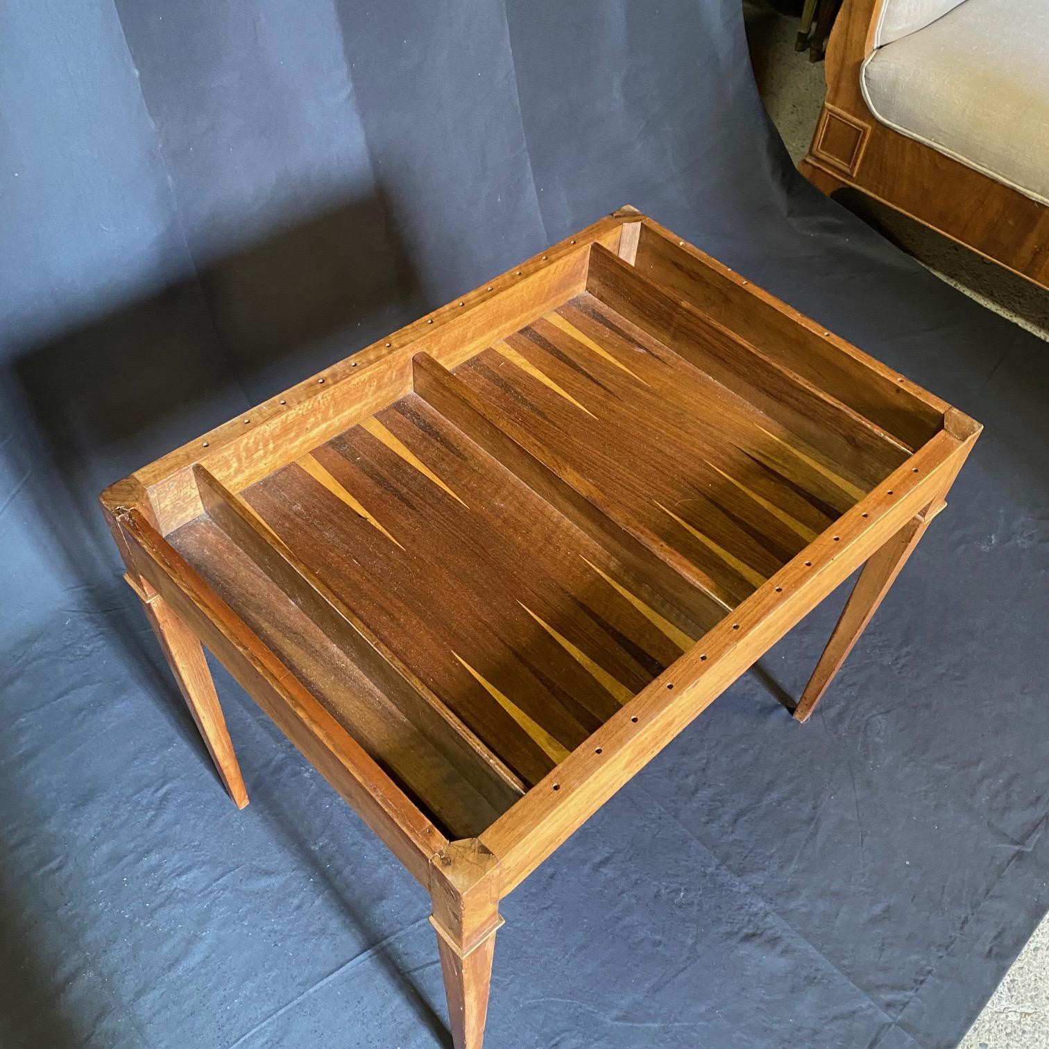 A French walnut game table from circa 1880 with 3 surface options: inlaid marquetry game board and embossed leather reversible top, or inlaid backgammon board on the interior. This French walnut game table captivates with its exquisite craftsmanship