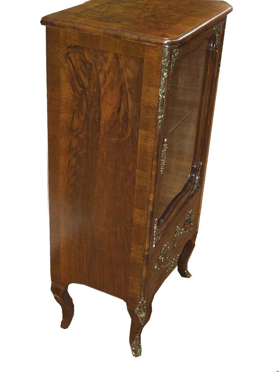 French walnut glass door display cabinet, the top, sides and drawer with burl walnut veneer and cross banded edges,  brass ormolu appliques on the front corner edges, feet and apron, interior with single shelf; glass door with brass appliques on