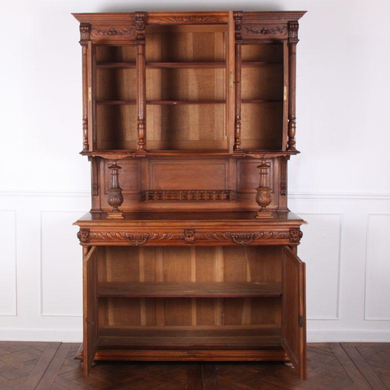 A French, solid walnut, hand carved Henri II-style buffet hutch, the lower case with a pair of doors carved with fruit below two drawers with gadrooned drawer fronts. The upper cabinet is raised on turned columns and features a finely-carved figural