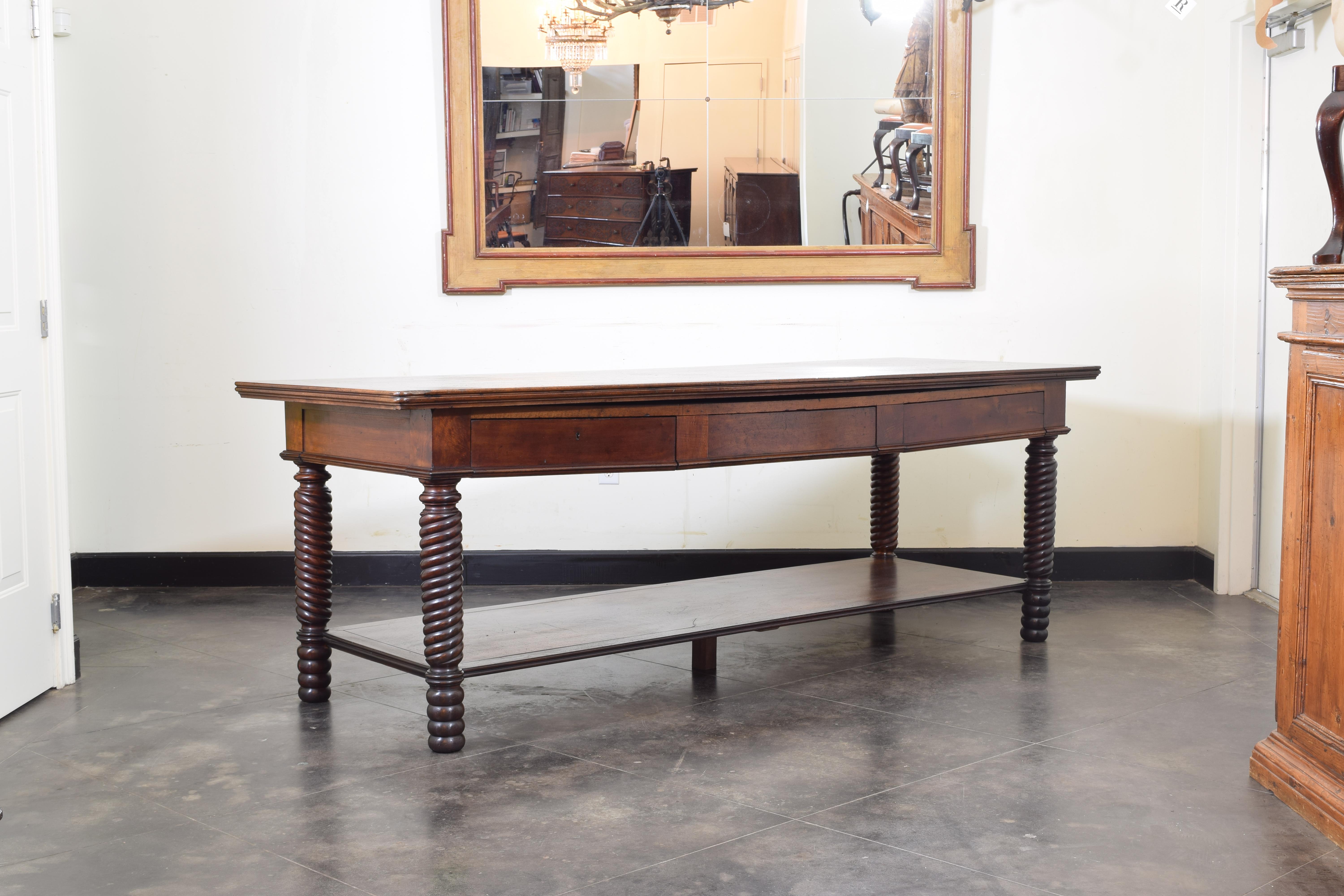 Large and in charge this drapers table has a rectangular top with a molded edge atop a frame housing three drawers, the legs with bold spiral turning, the lower shelf supported by a central brace.