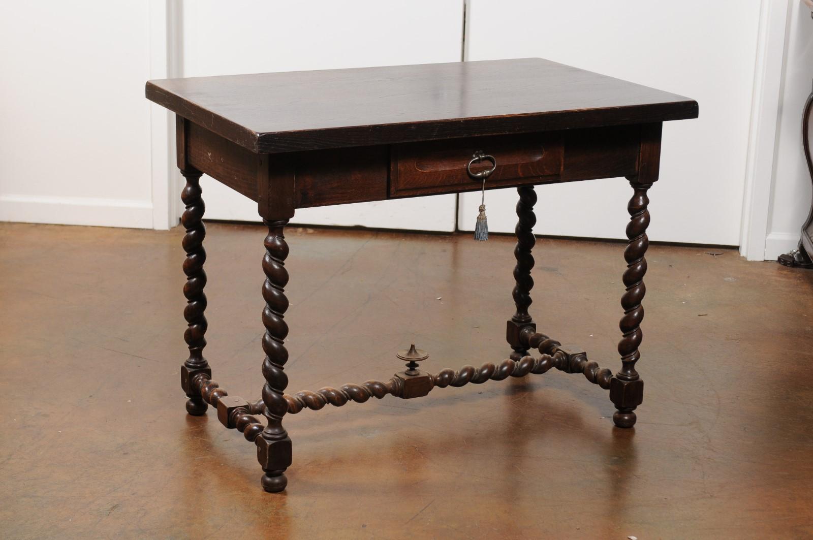 A French Louis XIII style walnut desk from the 19th century, with barley twist base. Born in France during the 19th century, this French walnut writing table features a rectangular top sitting above a single dovetailed drawer. The table is raised on
