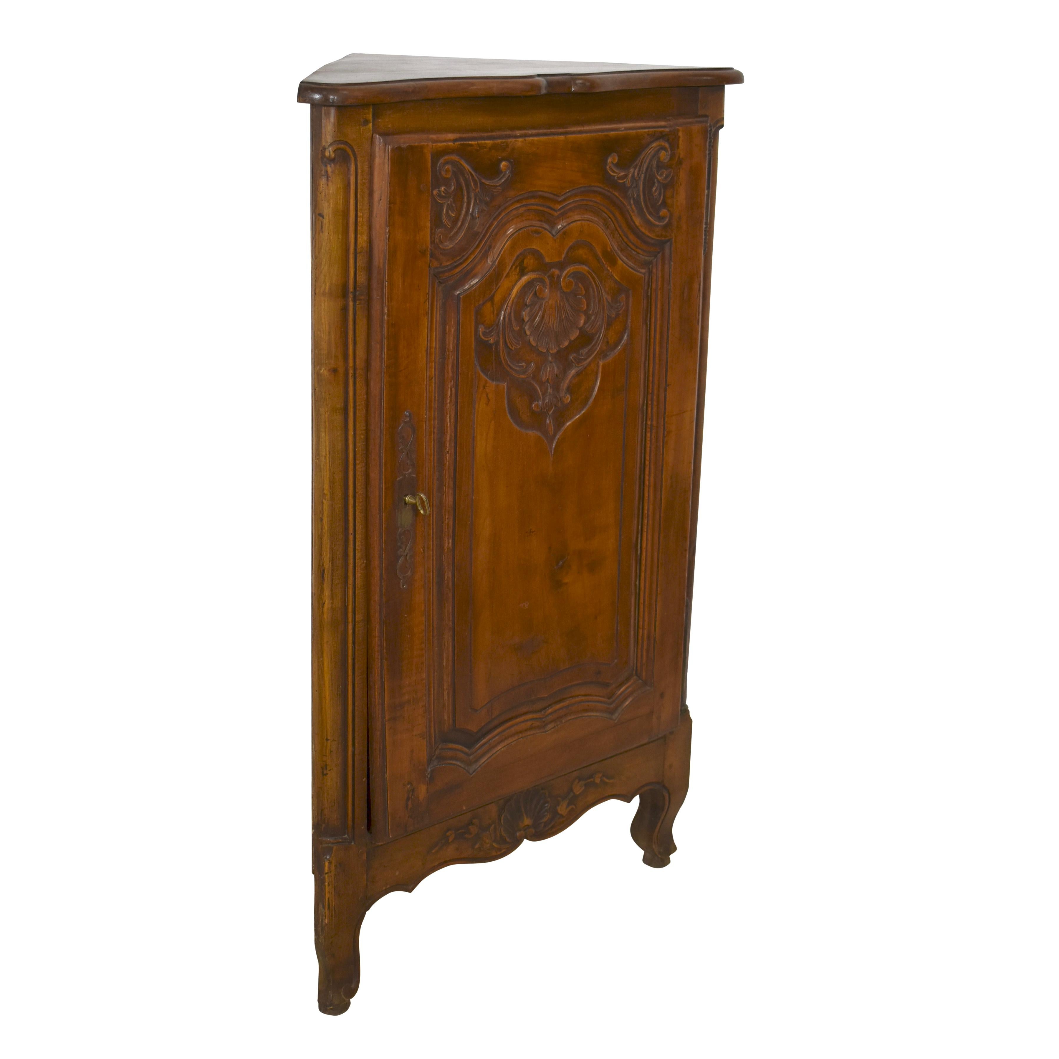 Featuring a Louis XV floral and shell motif, this petite corner cabinet showcases a small footprint and elegant design. The top front edge is beveled and scalloped. An arched raised panel door with a scalloped base reflects the scalloped apron