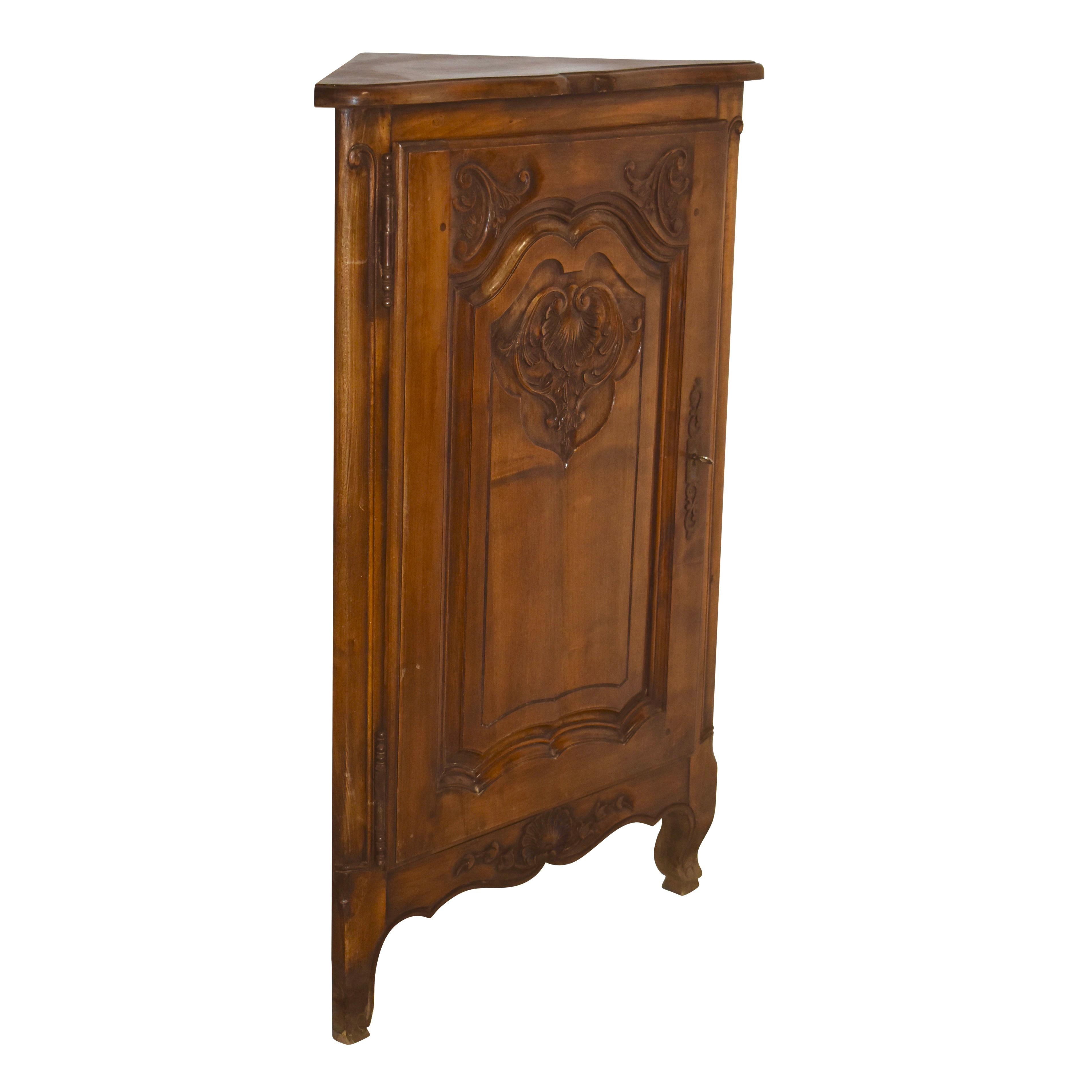 Featuring a Louis XV floral and shell motif, this petite corner cabinet showcases a small footprint and elegant design. The top front edge is beveled and scalloped. An arched raised panel door with a scalloped base reflects the scalloped apron