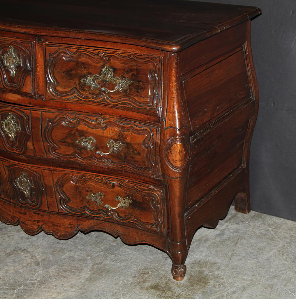 A rare French Louis XV carved walnut Bombay serpentine Provincial five-drawer commode, with beautifully carved moldings, paneled sides, and scroll feet, with early brass handles and escutcheons, and a magnificently cared serpentine rail.