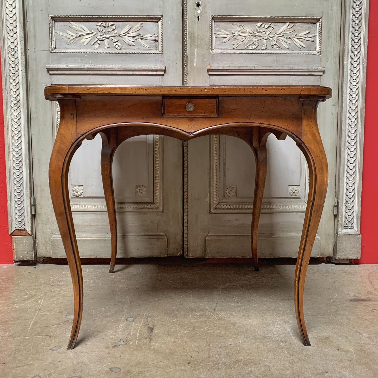 A walnut Louis XV style game table from France with a red tooled leather top and four drawers and four pull out drink holders.