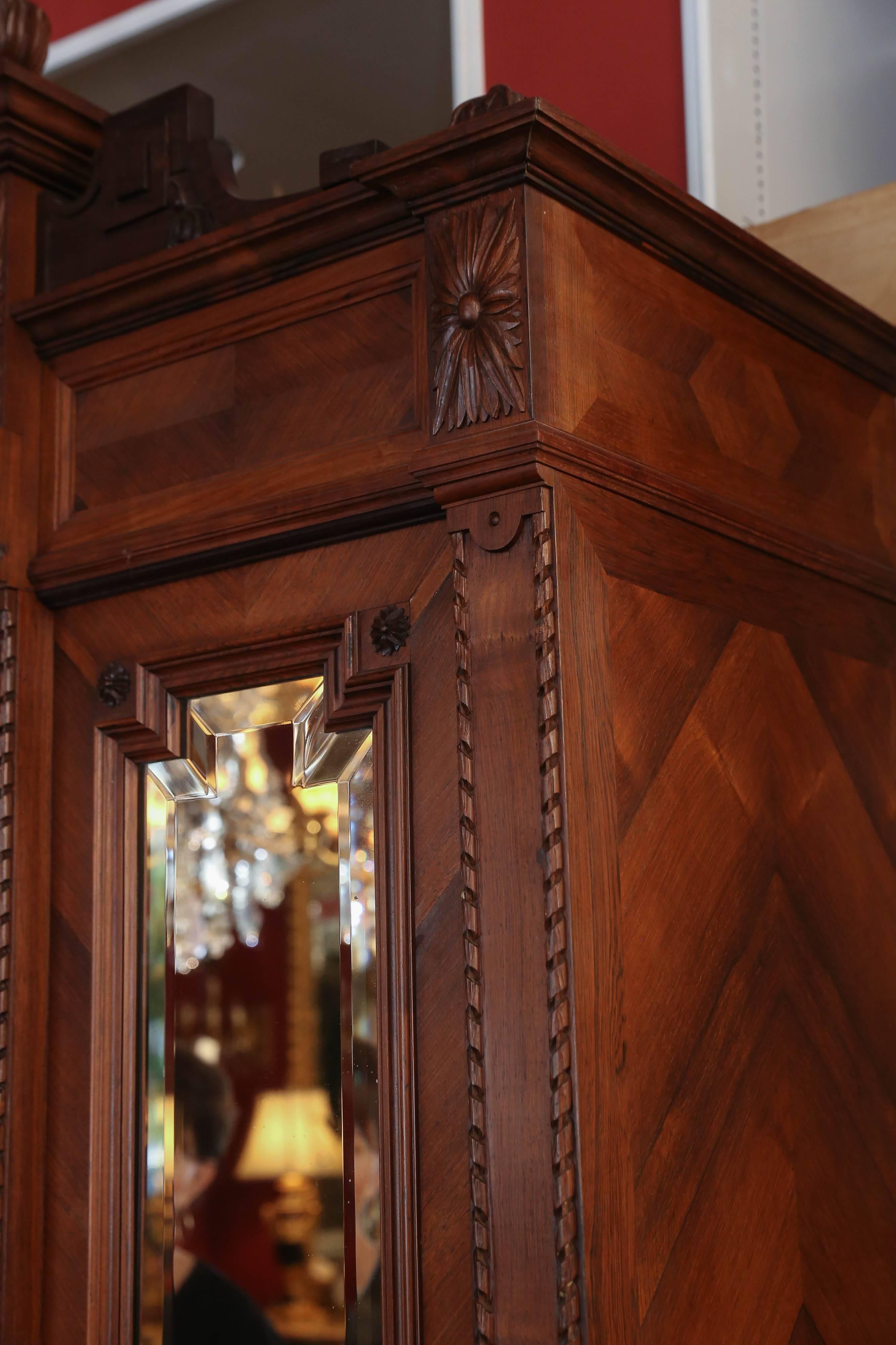 Large triple mirror armoire made of walnut with a pediment
wood carved with a circular motif with flowers and ribbons.
All the mirrors are original, bevelled and clear. A finely
carved gadrooned edging runs the vertical length of this
piece. It